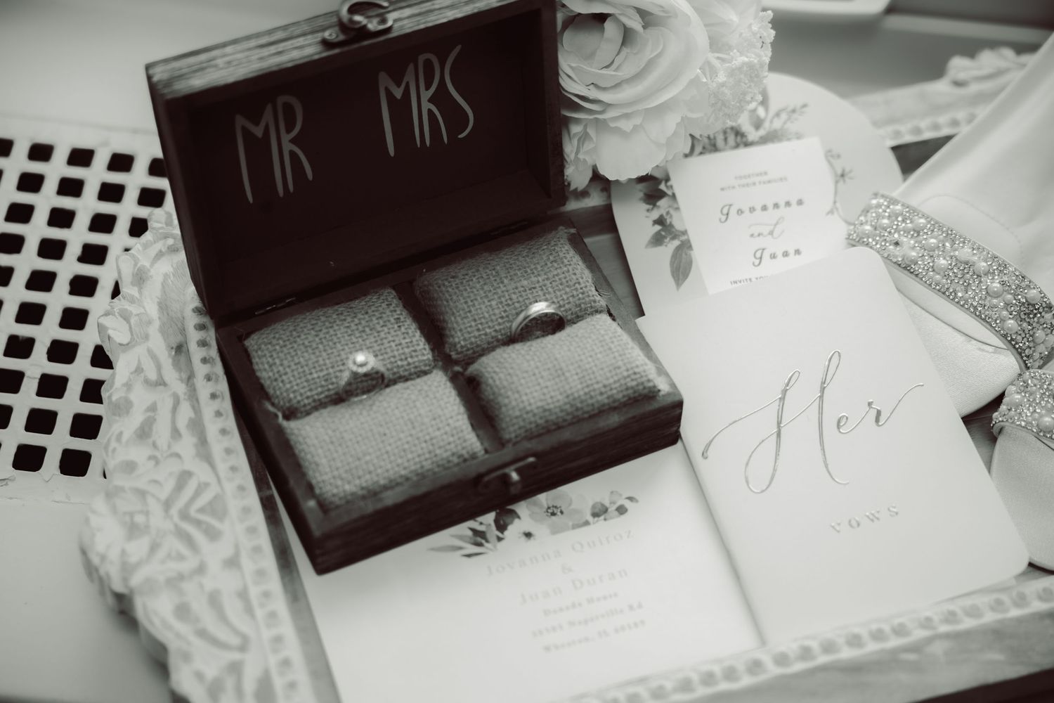 Black and white photo of wedding rings in Mr and Mrs box with vow booklet.