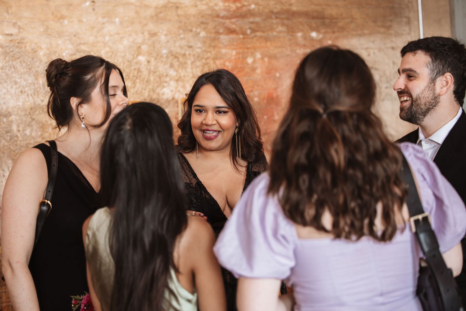 Group of young professionals socializing and laughing at an upscale networking event.