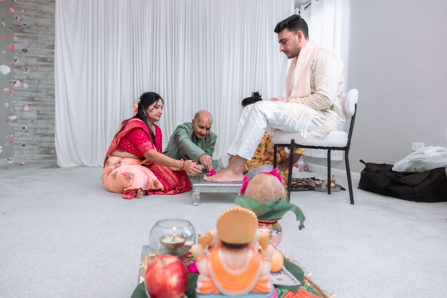 Couple performs traditional Hindu puja ritual with priest and ceremonial items during Indian wedding.