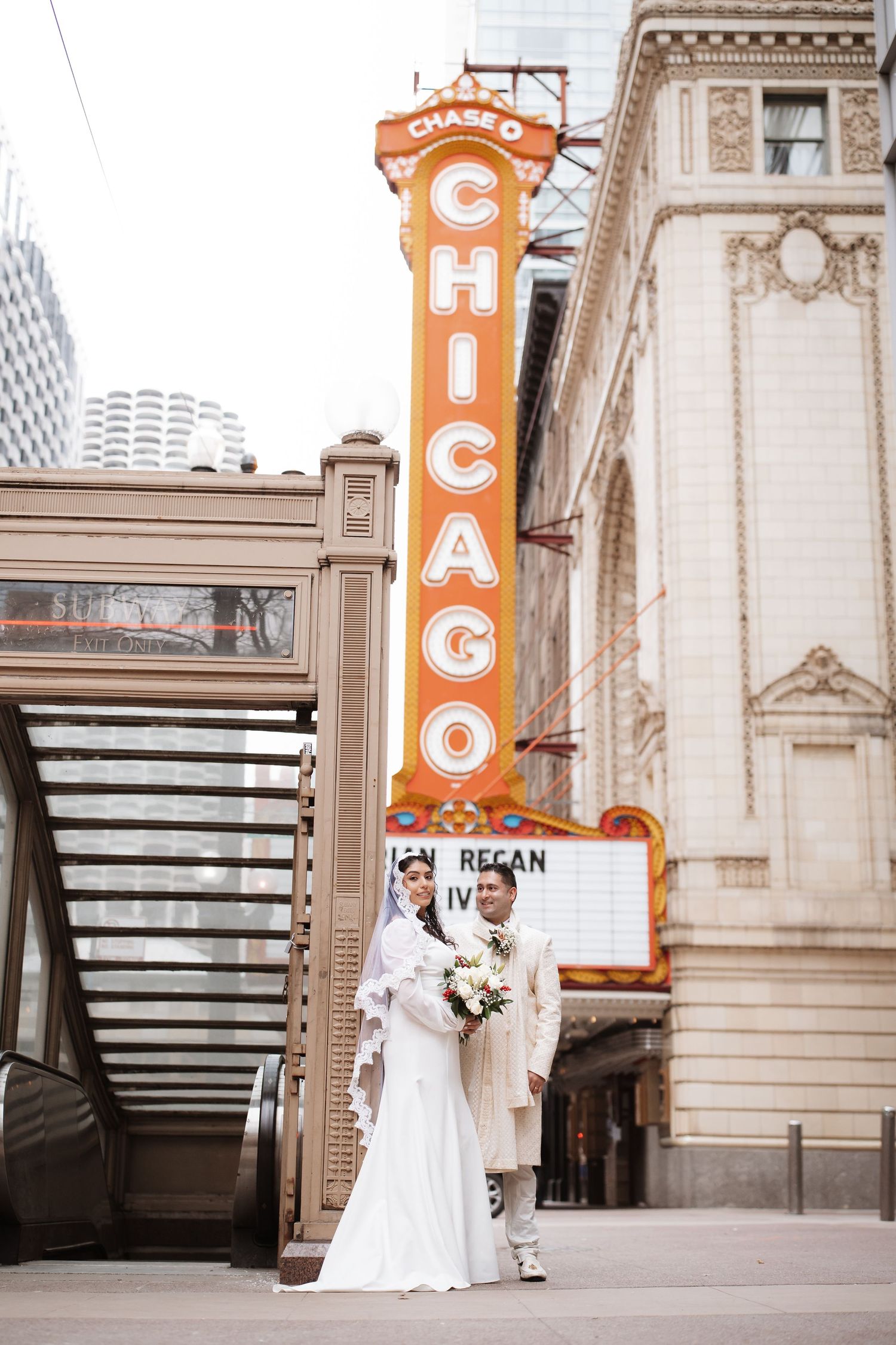 Wedding couple poses in front of the famous Chicago Theatre orange neon sign downtown.
