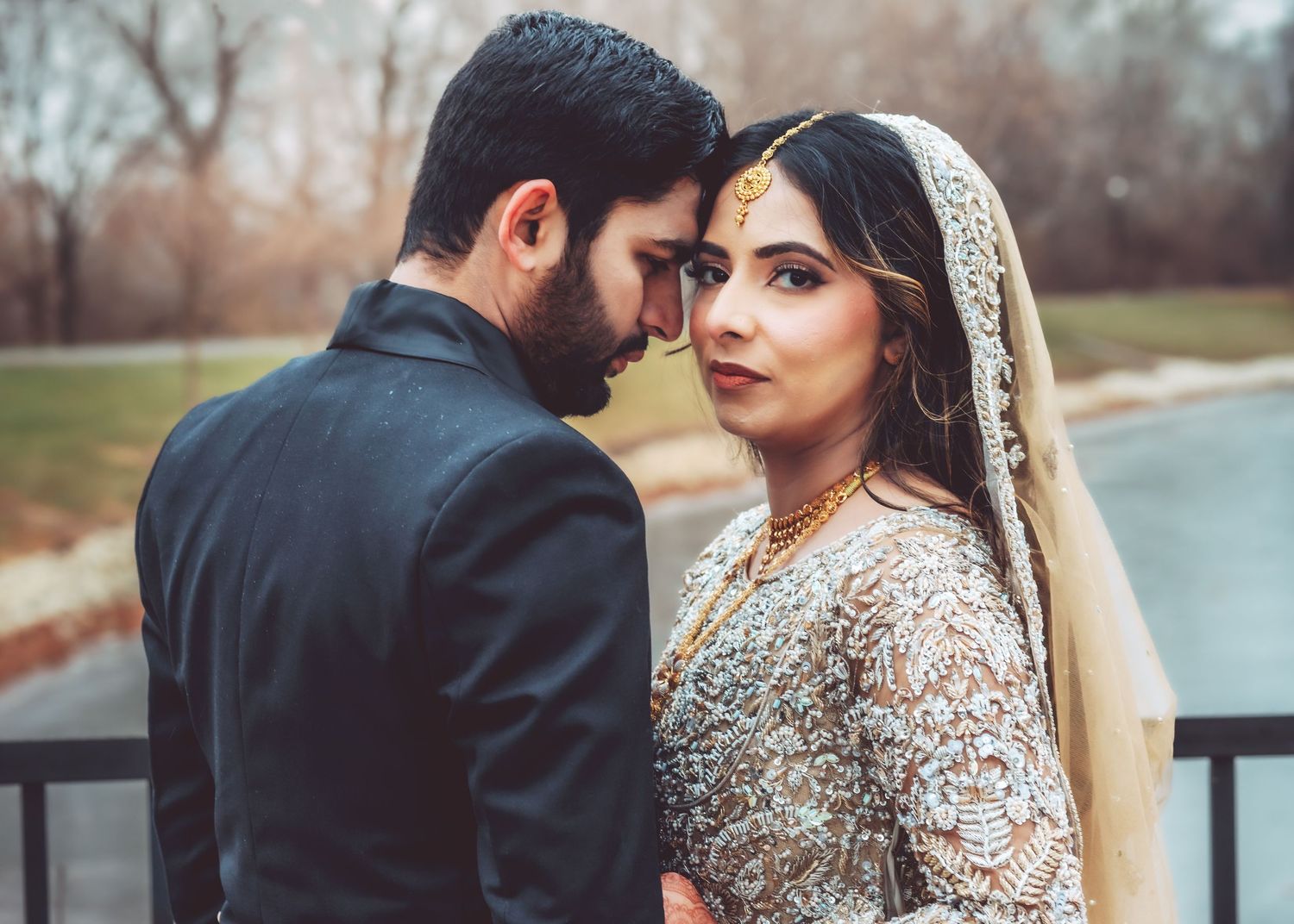 South Asian wedding couple share intimate forehead touch moment wearing traditional bridal and groom attire.