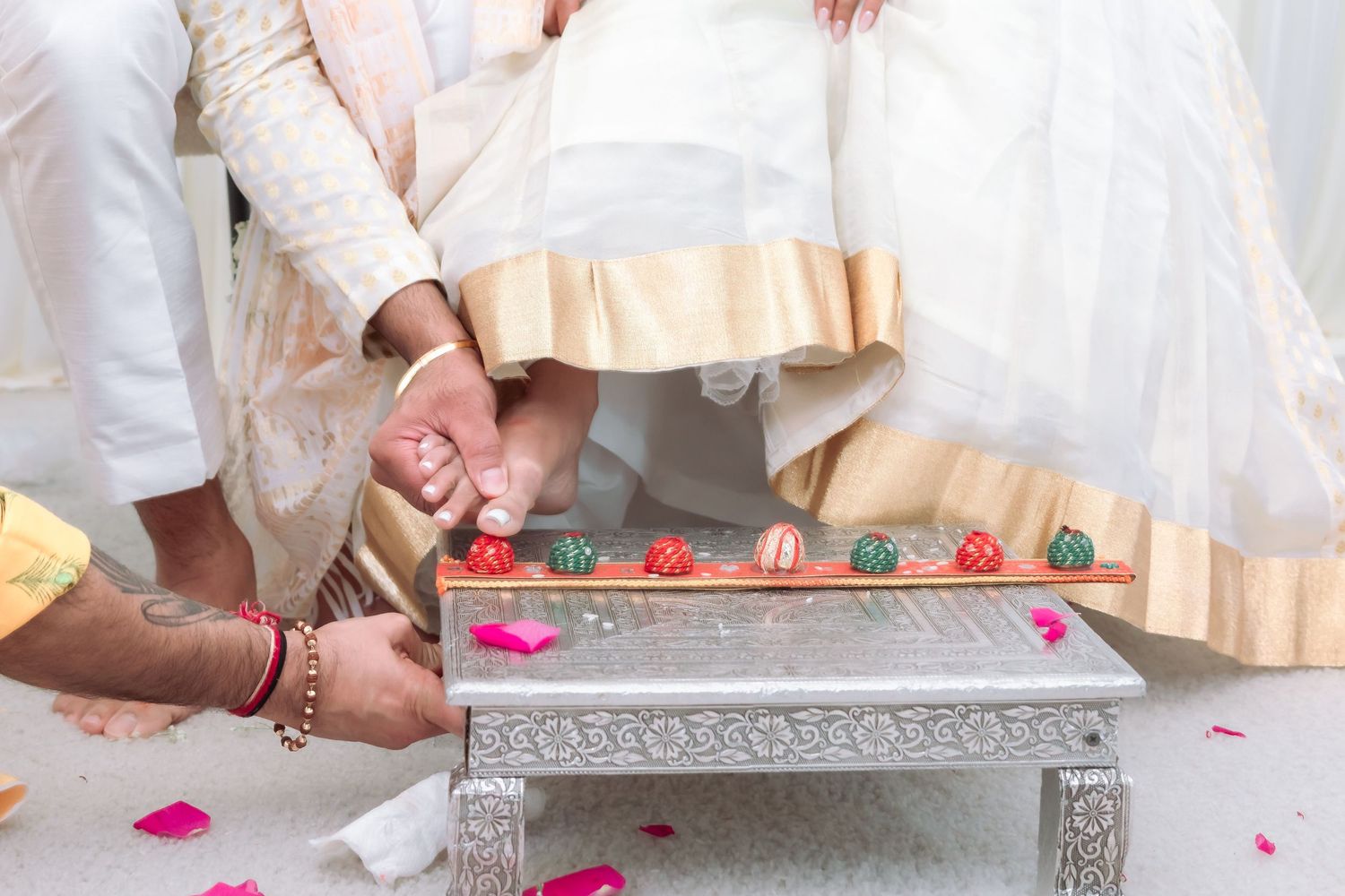 Indian wedding ritual with colorful toe rings being placed on bride's feet during traditional ceremony.