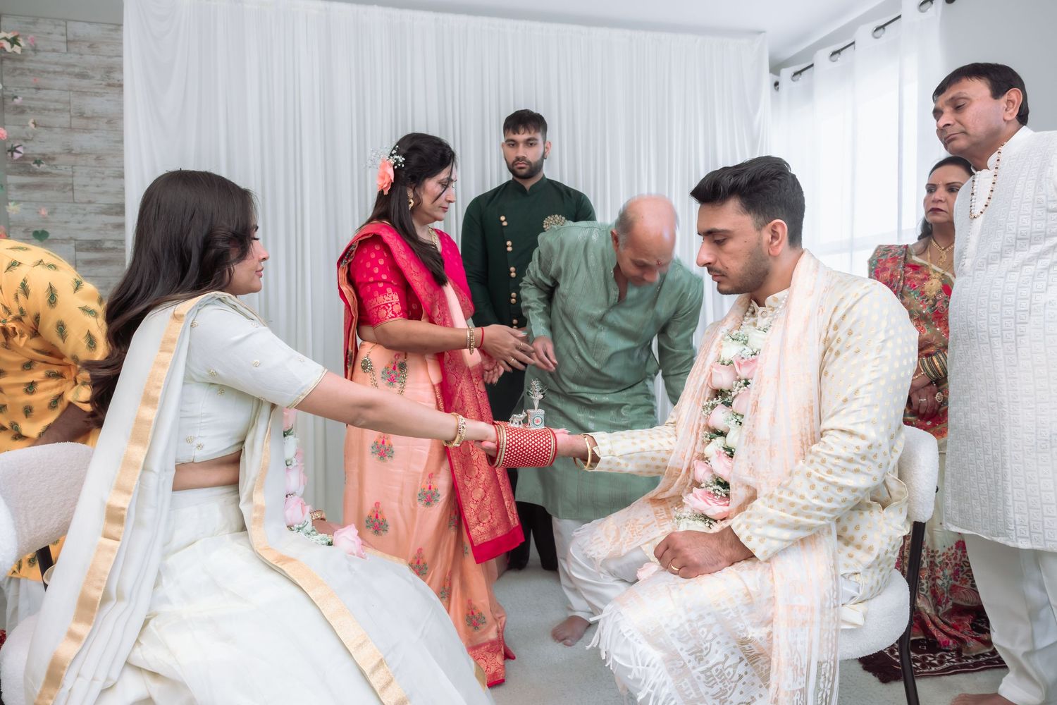 Indian wedding ceremony with family members exchanging gifts and blessings with bride and groom in traditional attire.