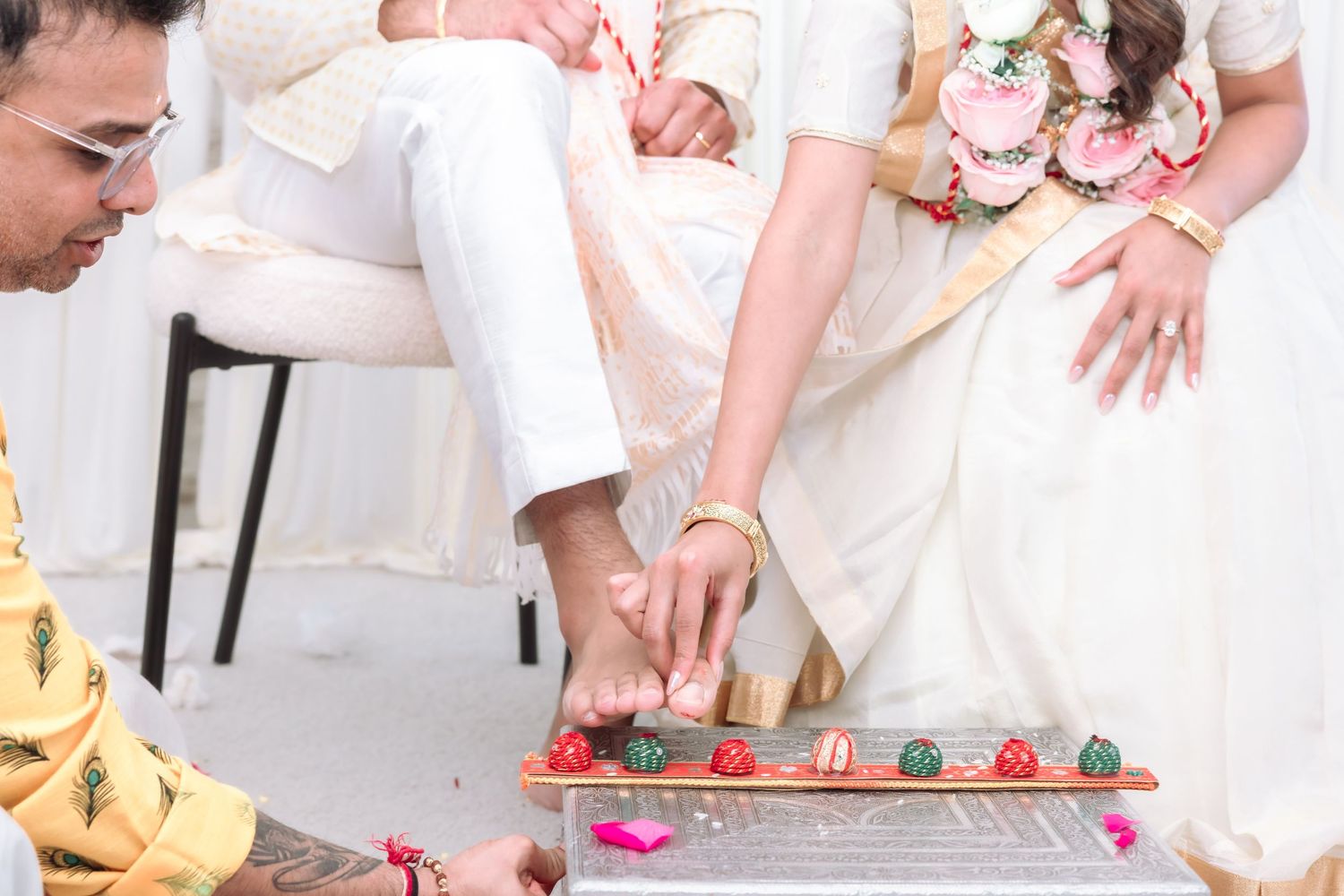 Close-up of Indian wedding ritual with hands performing ceremonial foot washing with flower-adorned tray.