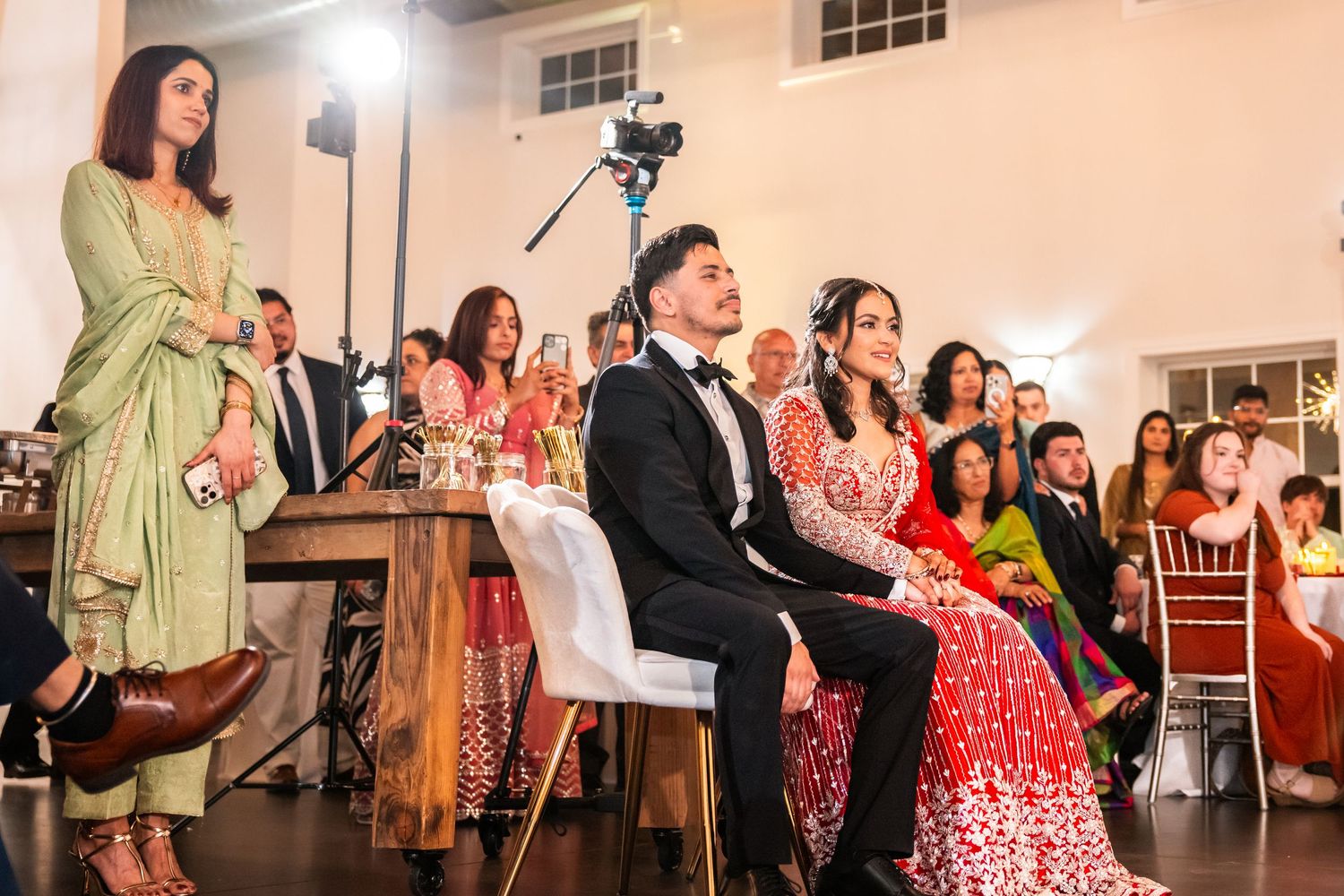 Bride and groom in traditional South Asian attire at indoor wedding reception.