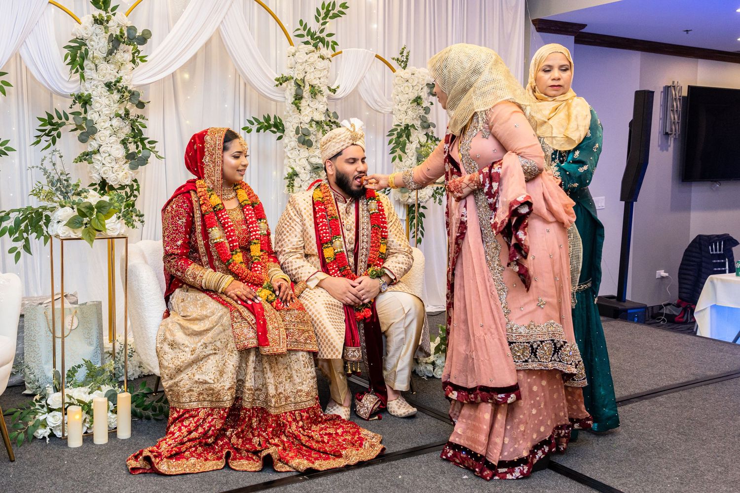 South Asian wedding ceremony with bride and groom in traditional red and gold attire.
