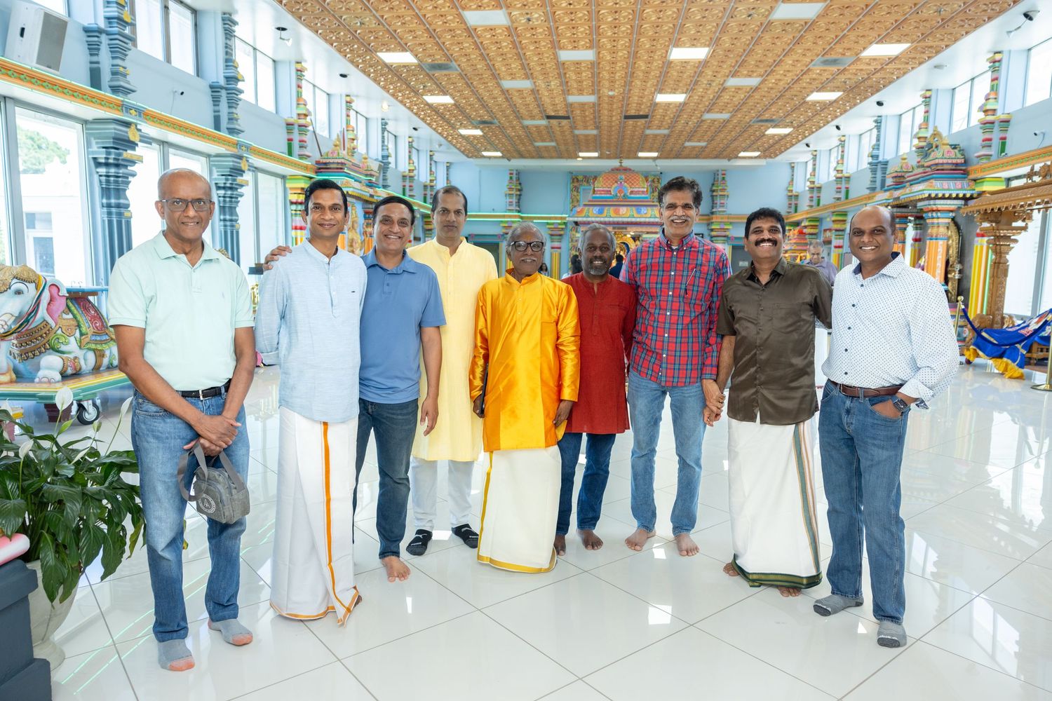 Group of men posing inside a colorful South Indian Hindu temple with ornate architecture.