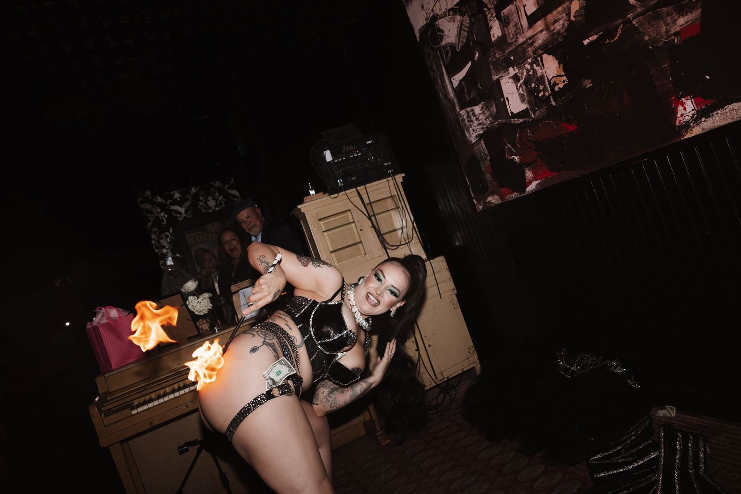 Performer in dark costume poses with fire during a dramatic nightclub stage show.