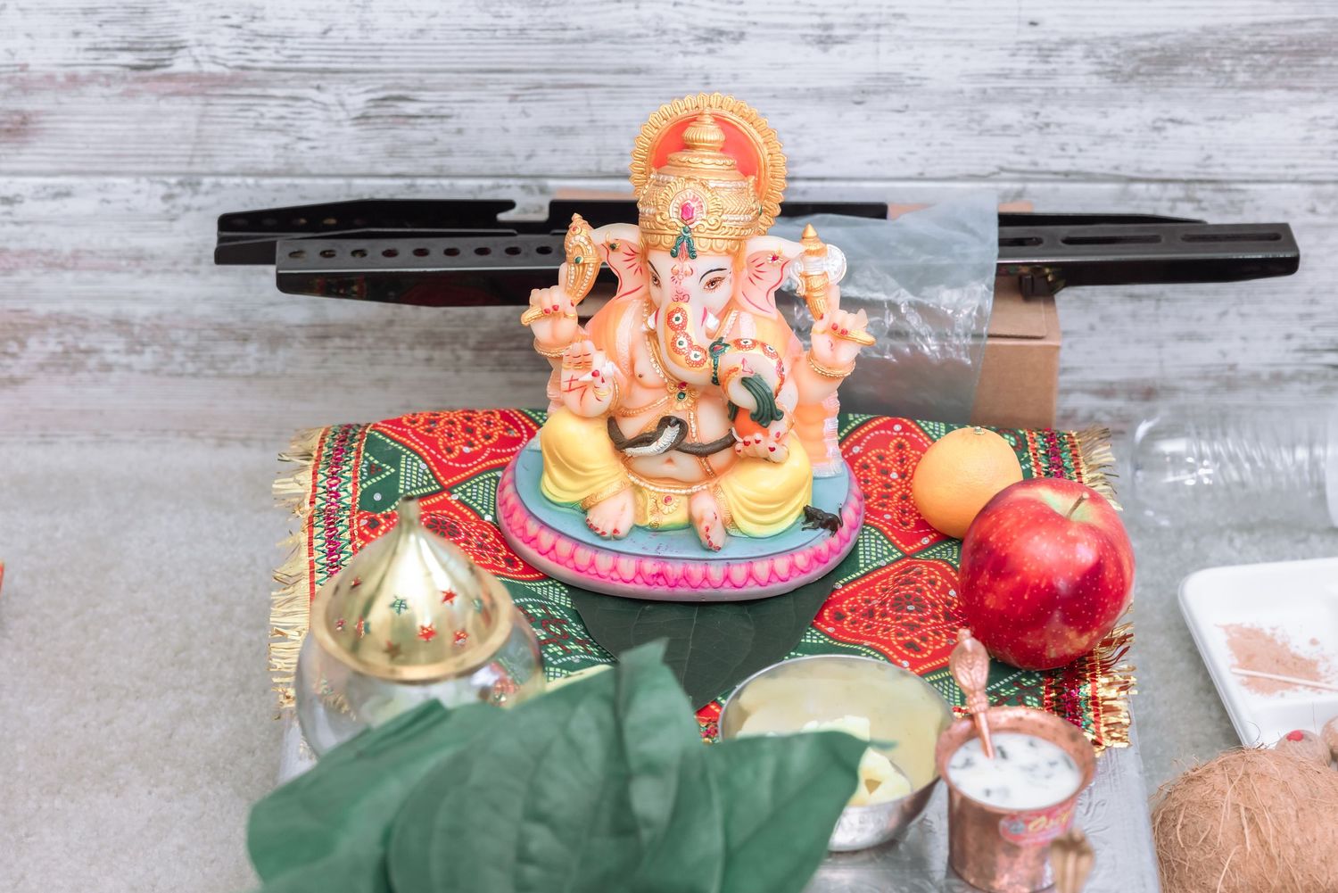 Colorful Ganesha idol surrounded by fruits and offerings during Hindu puja ceremony.