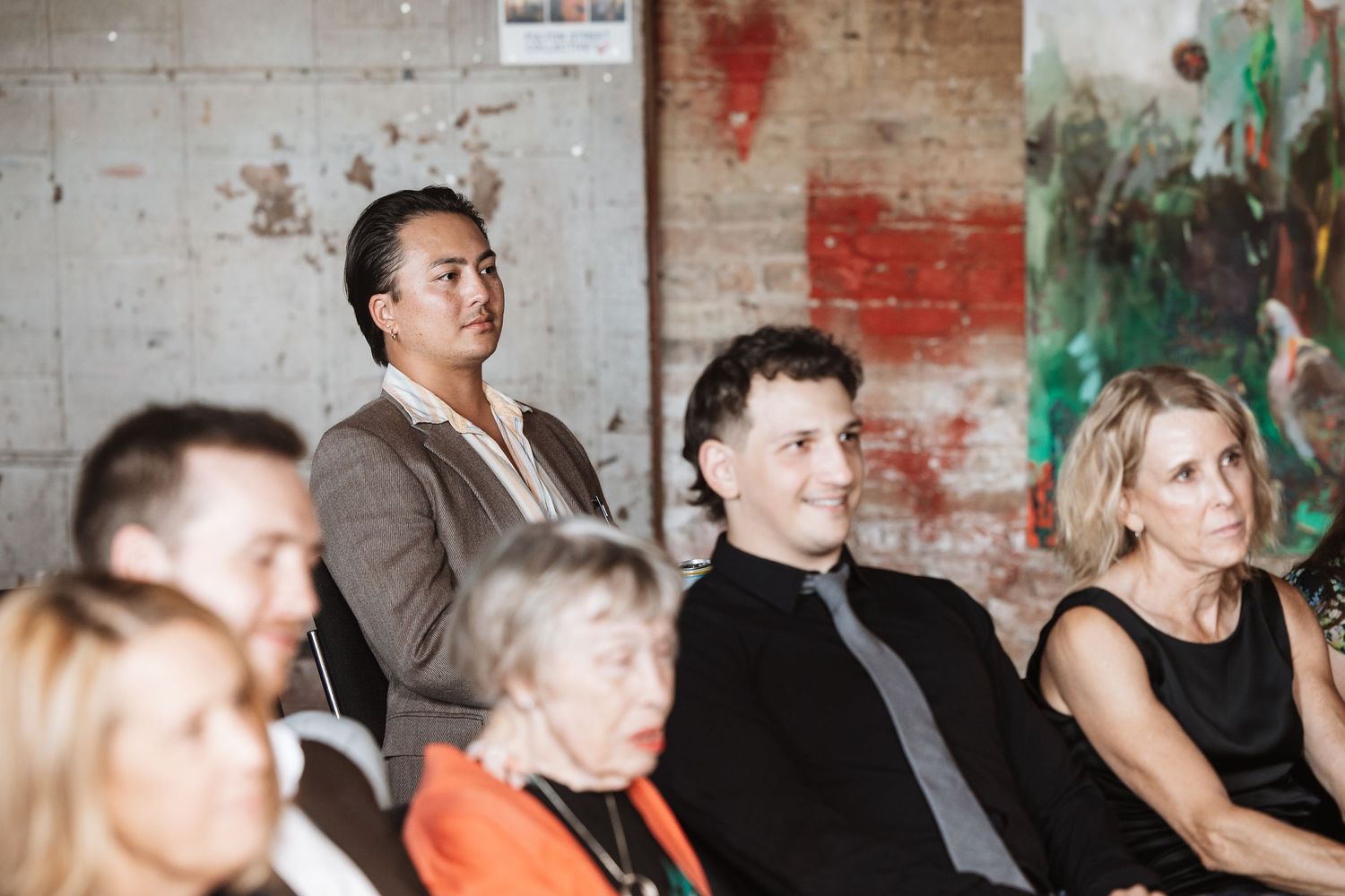 Audience members seated at an indoor event, attentively watching a presentation in a modern industrial venue.