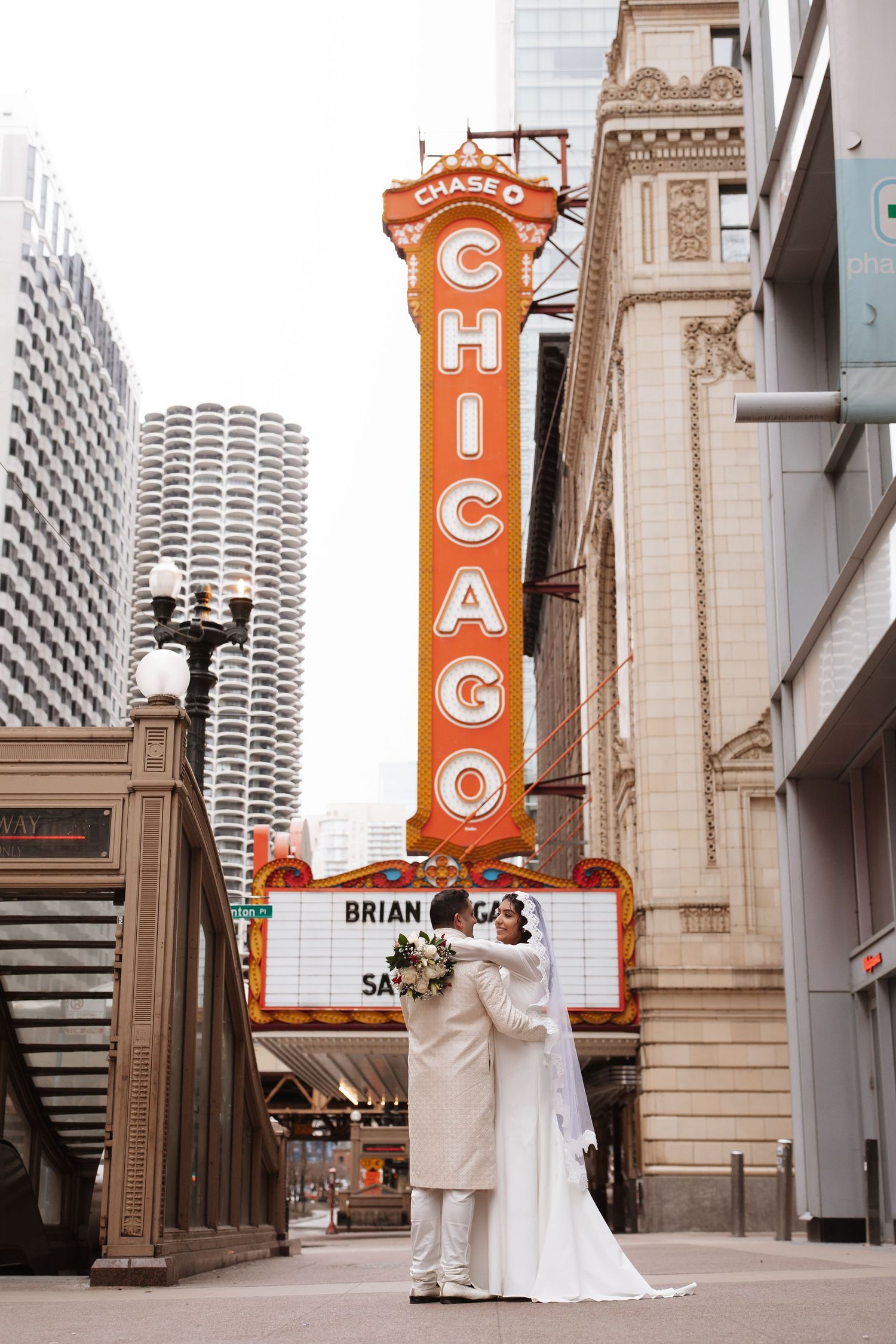 Bride and groom share a kiss beneath the tall Chicago Theatre vertical marquee sign.