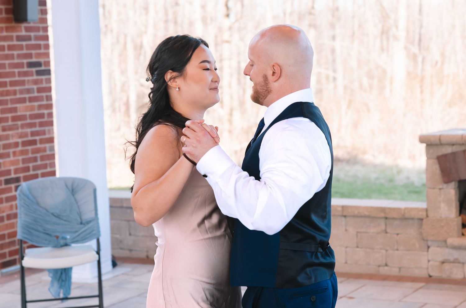 Groom tenderly holds bride's face as they share an intimate moment at outdoor wedding reception.