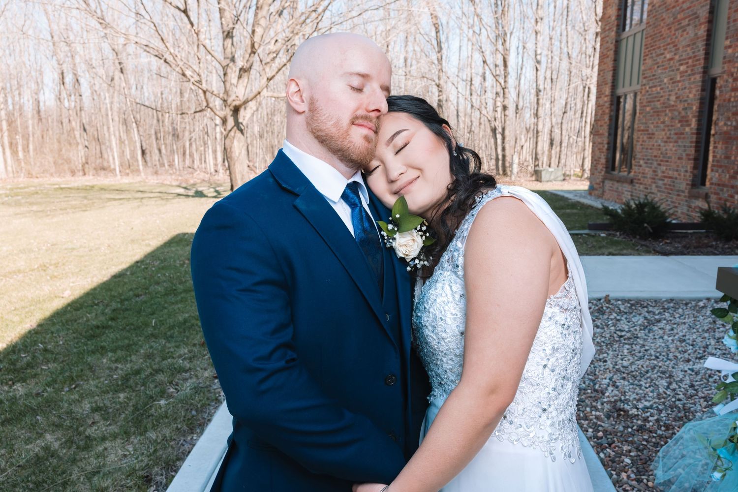 Newlyweds sharing a tender romantic moment outdoors on their wedding day.
