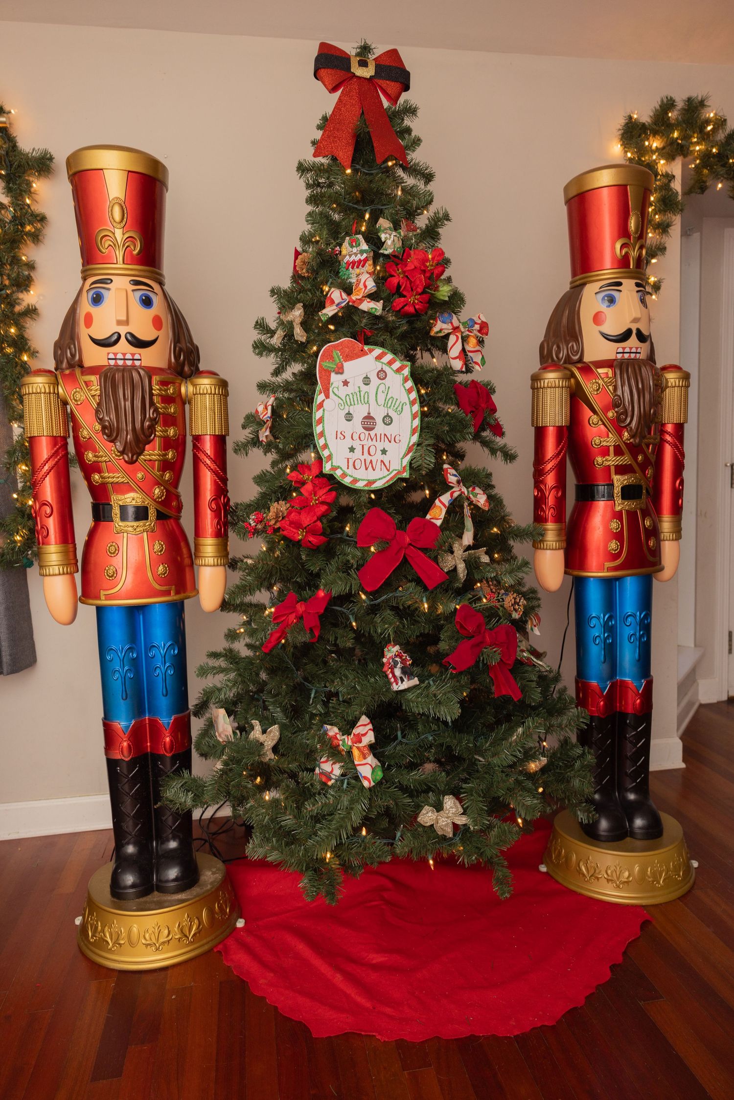 Beautifully decorated Christmas tree flanked by two large nutcracker figurines with red holiday skirt.