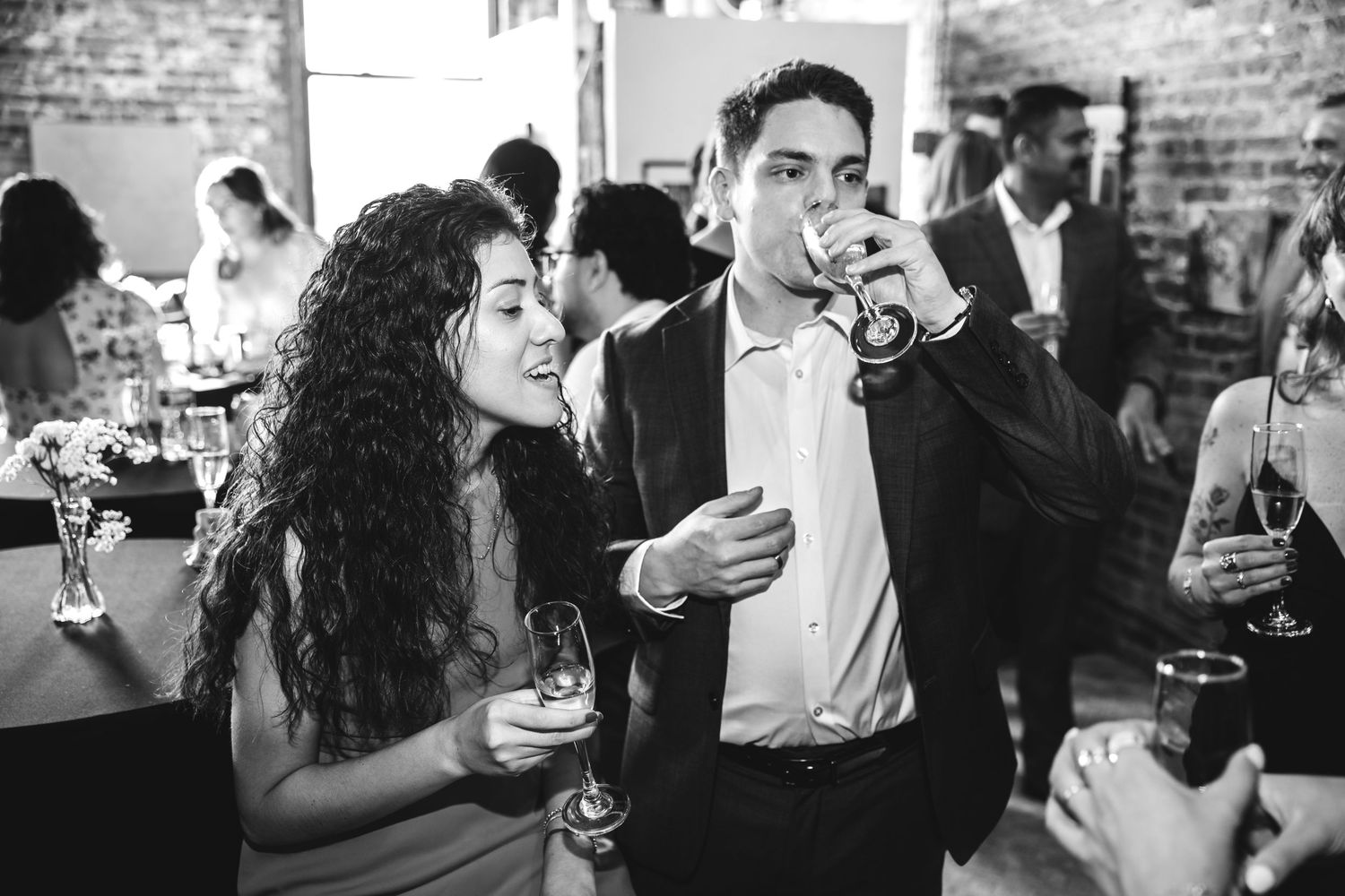 Black and white photo of a couple enjoying drinks at a social gathering.