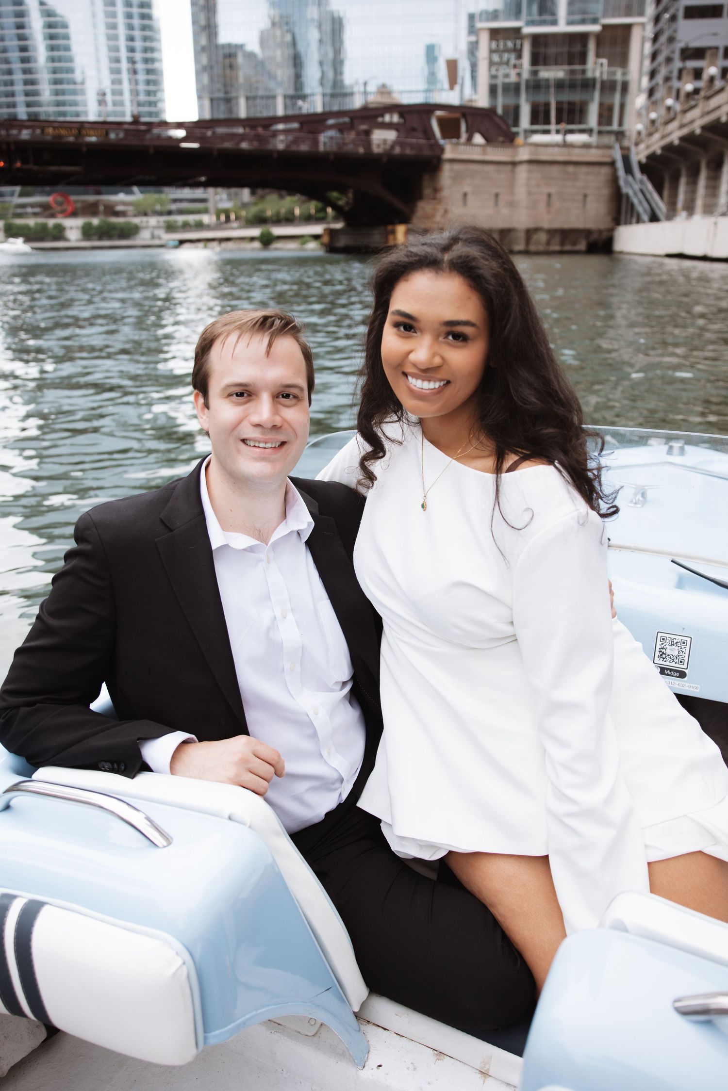 Smiling interracial couple posing together on a classic blue boat on the Chicago River with skyline views.