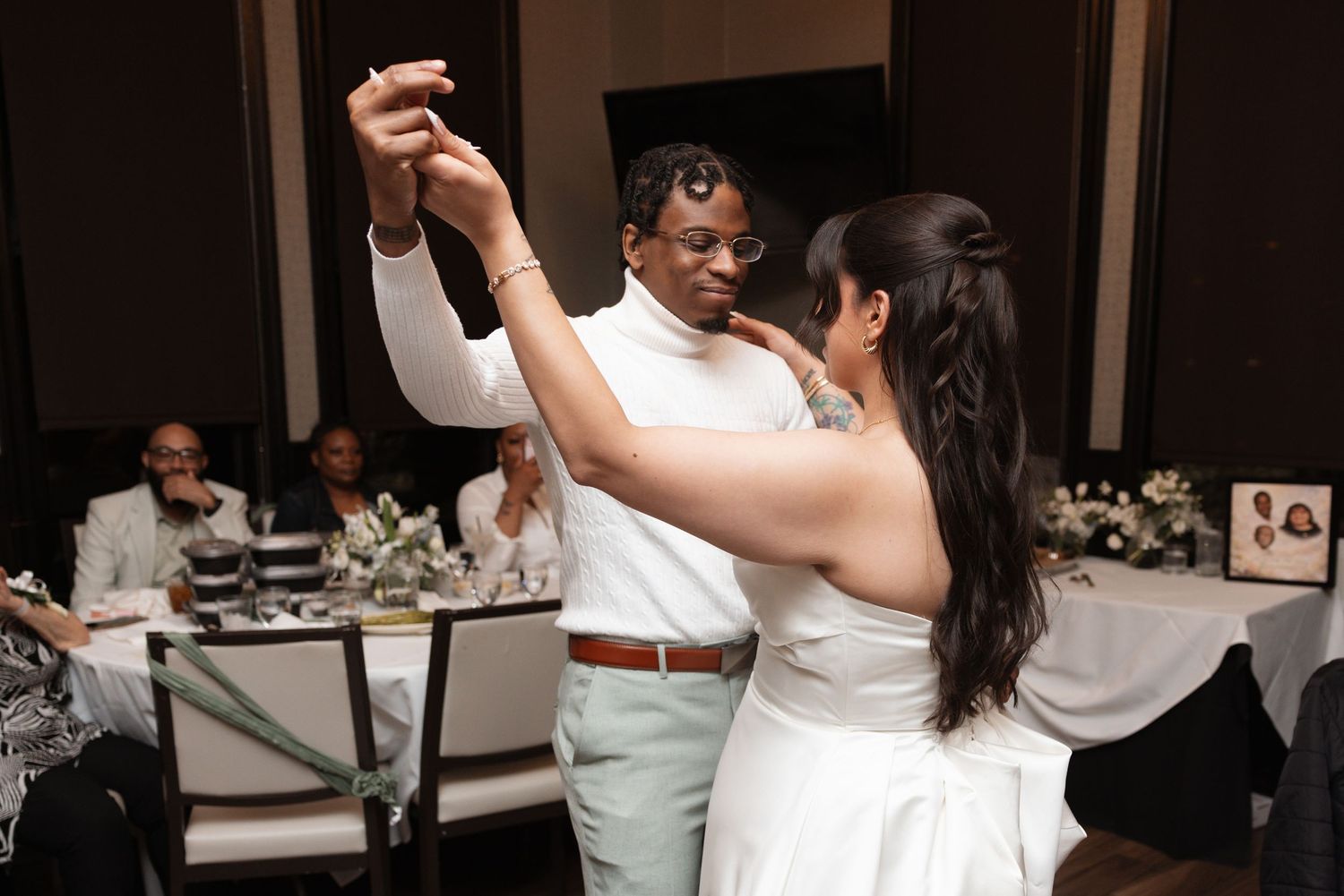 Bride and groom sharing first dance at wedding reception with guests watching.