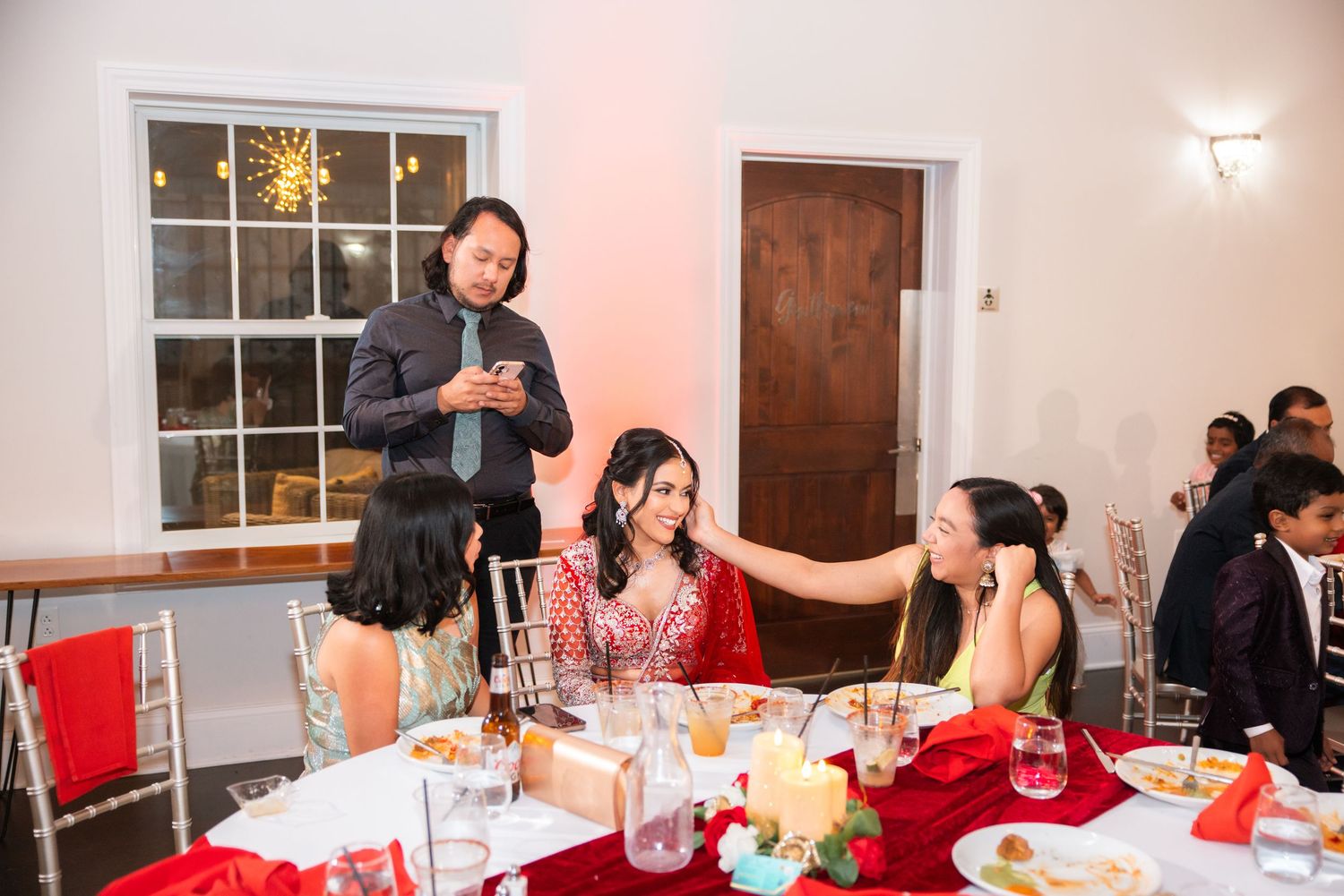 Man speaking to women seated at decorated wedding reception dinner table.