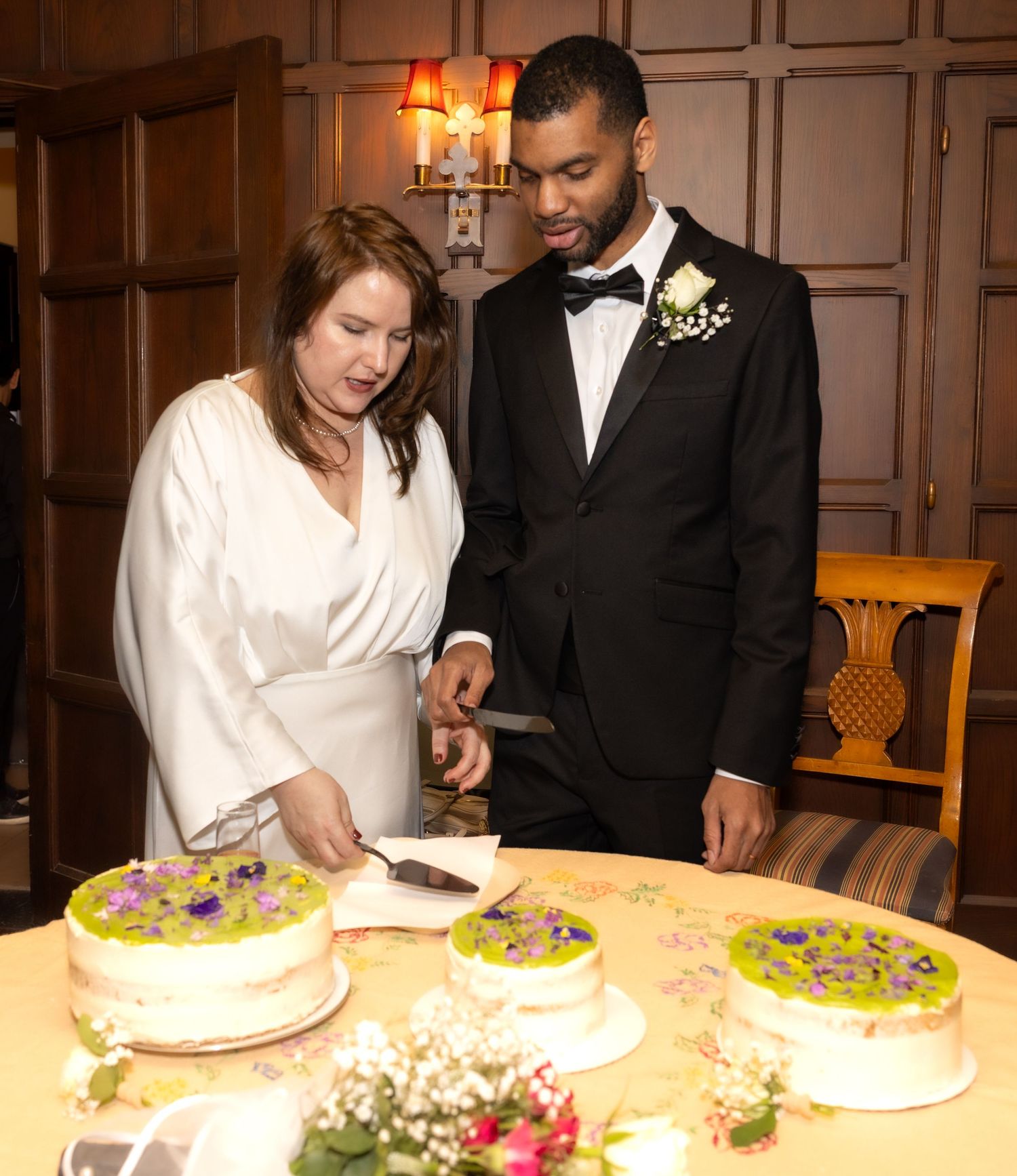 Bride and groom cutting a decorated wedding cake together at an elegant indoor reception.