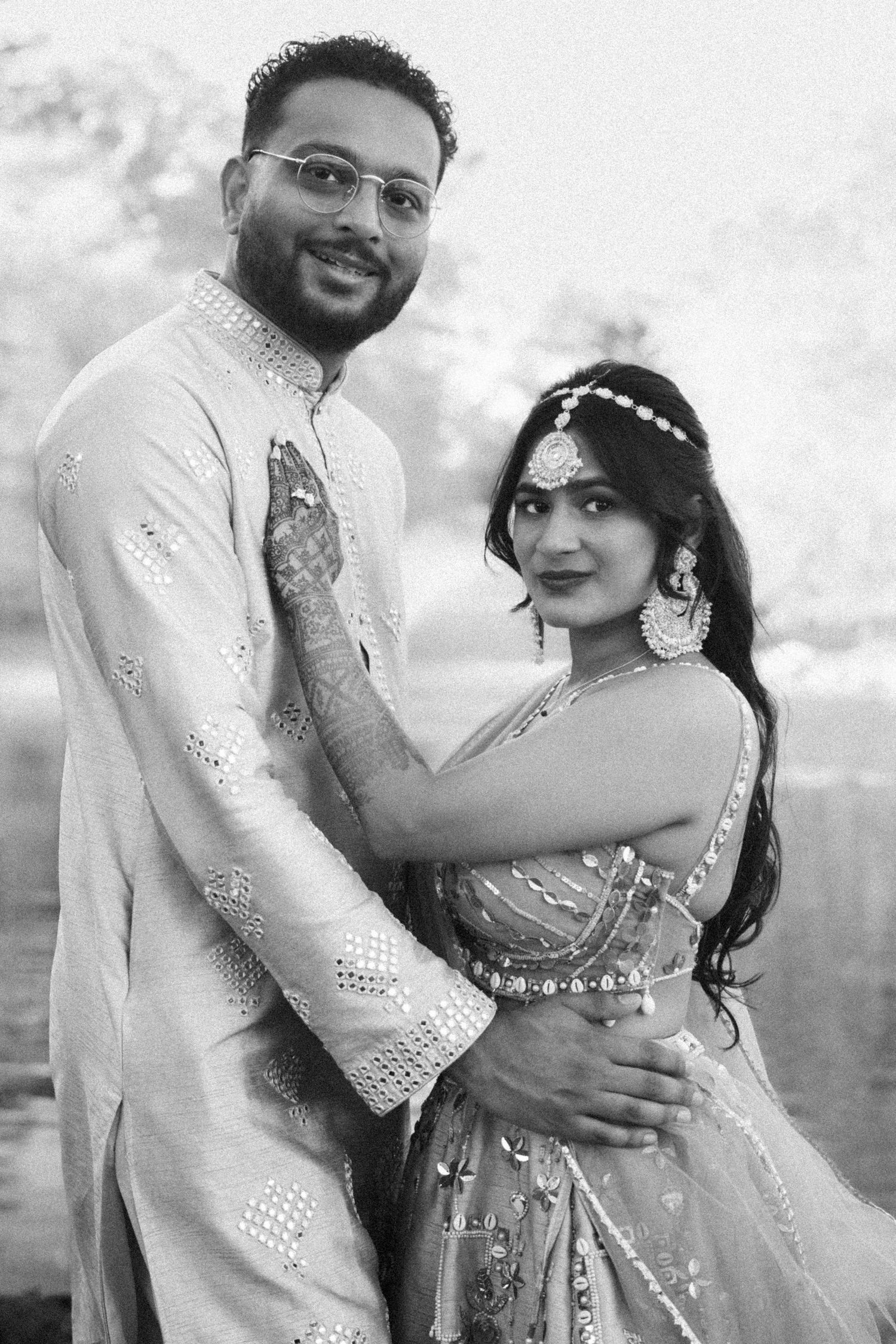 Black and white close-up of Indian couple in traditional wedding attire posing together.