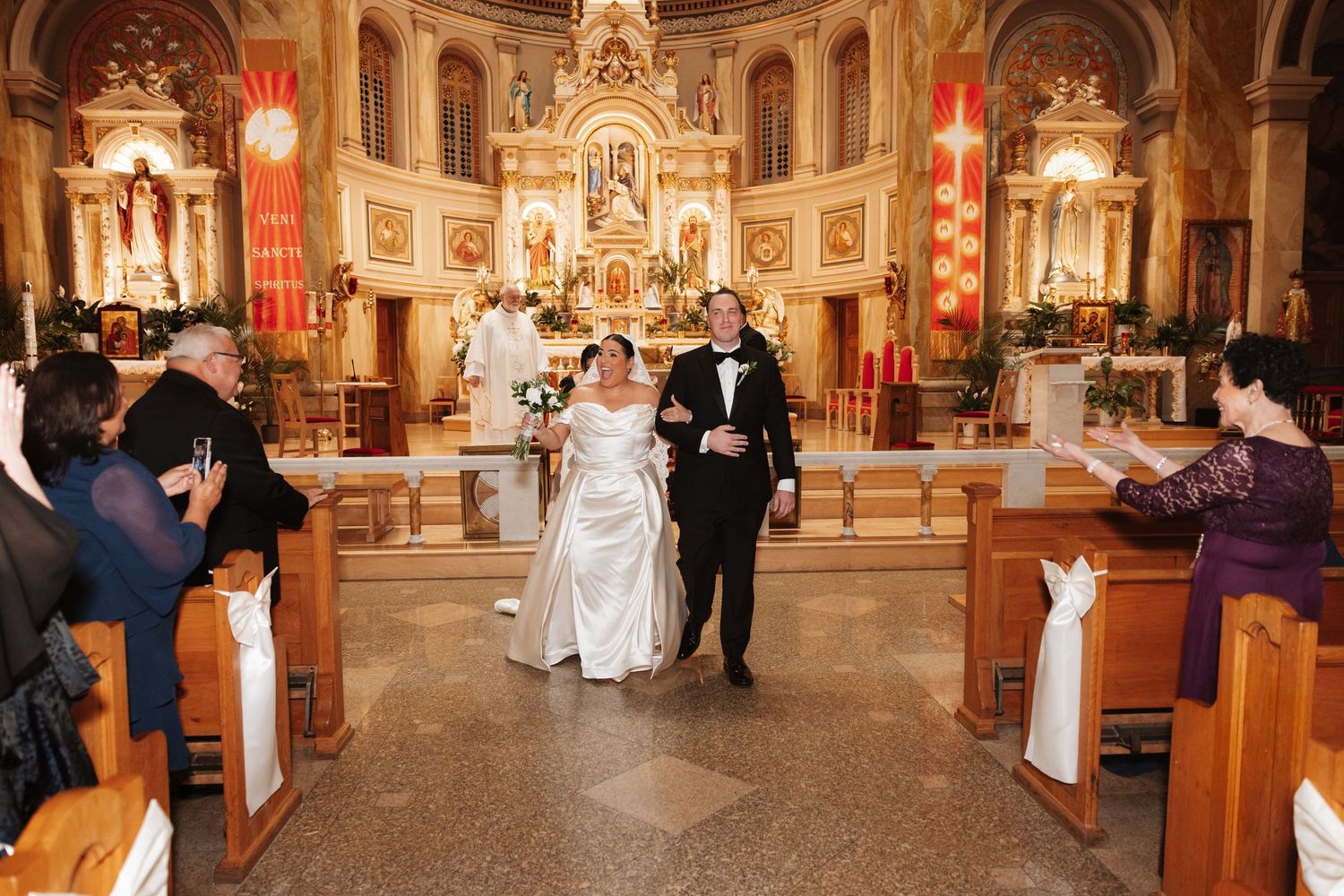 Bride and groom walk down church aisle after wedding ceremony.