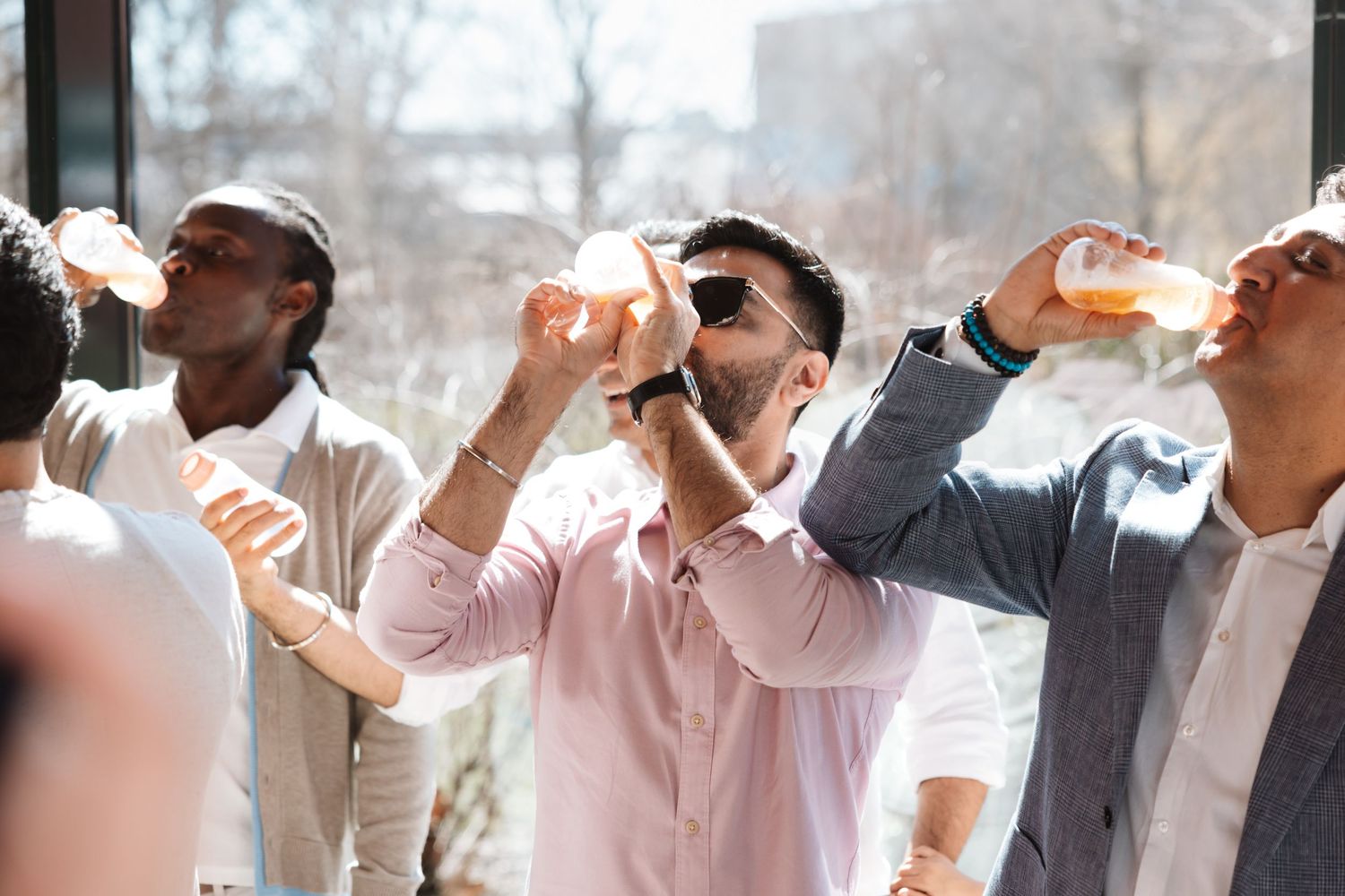 Group of men drinking beverages and celebrating together at a lively indoor social gathering event.
