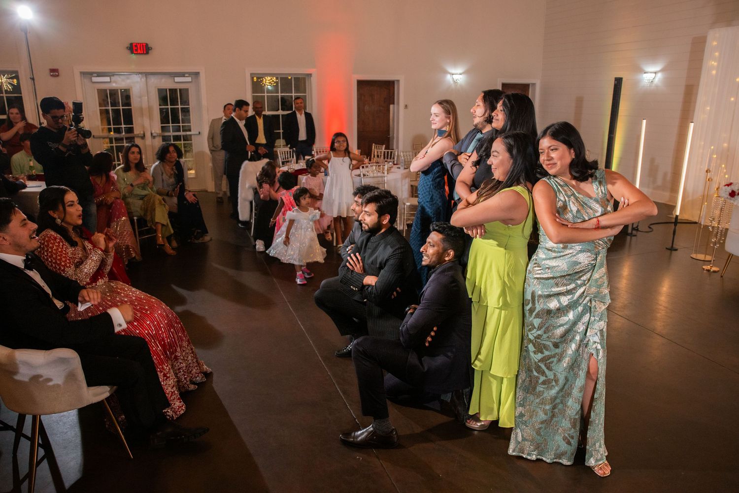 Wedding guests posing together on the dance floor during an indoor reception celebration.