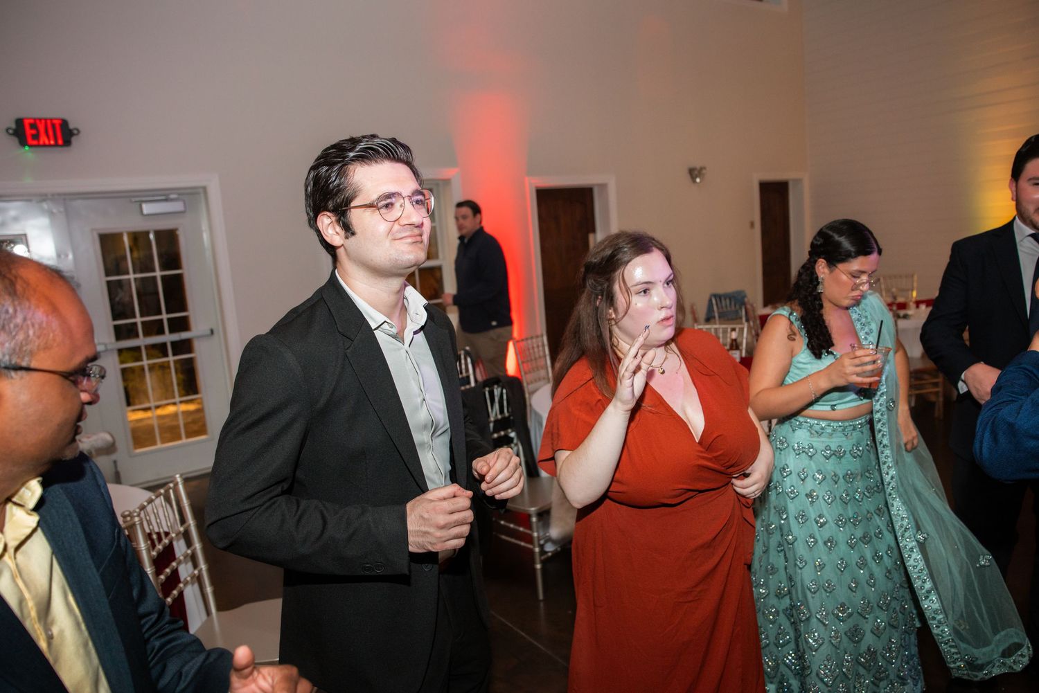 Wedding guests in formal attire socialize and enjoy drinks at an elegant evening reception.