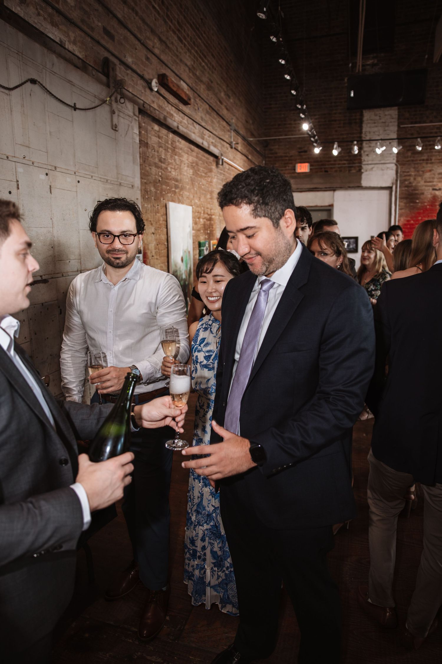 Guests toast with champagne glasses at a sophisticated indoor cocktail party.