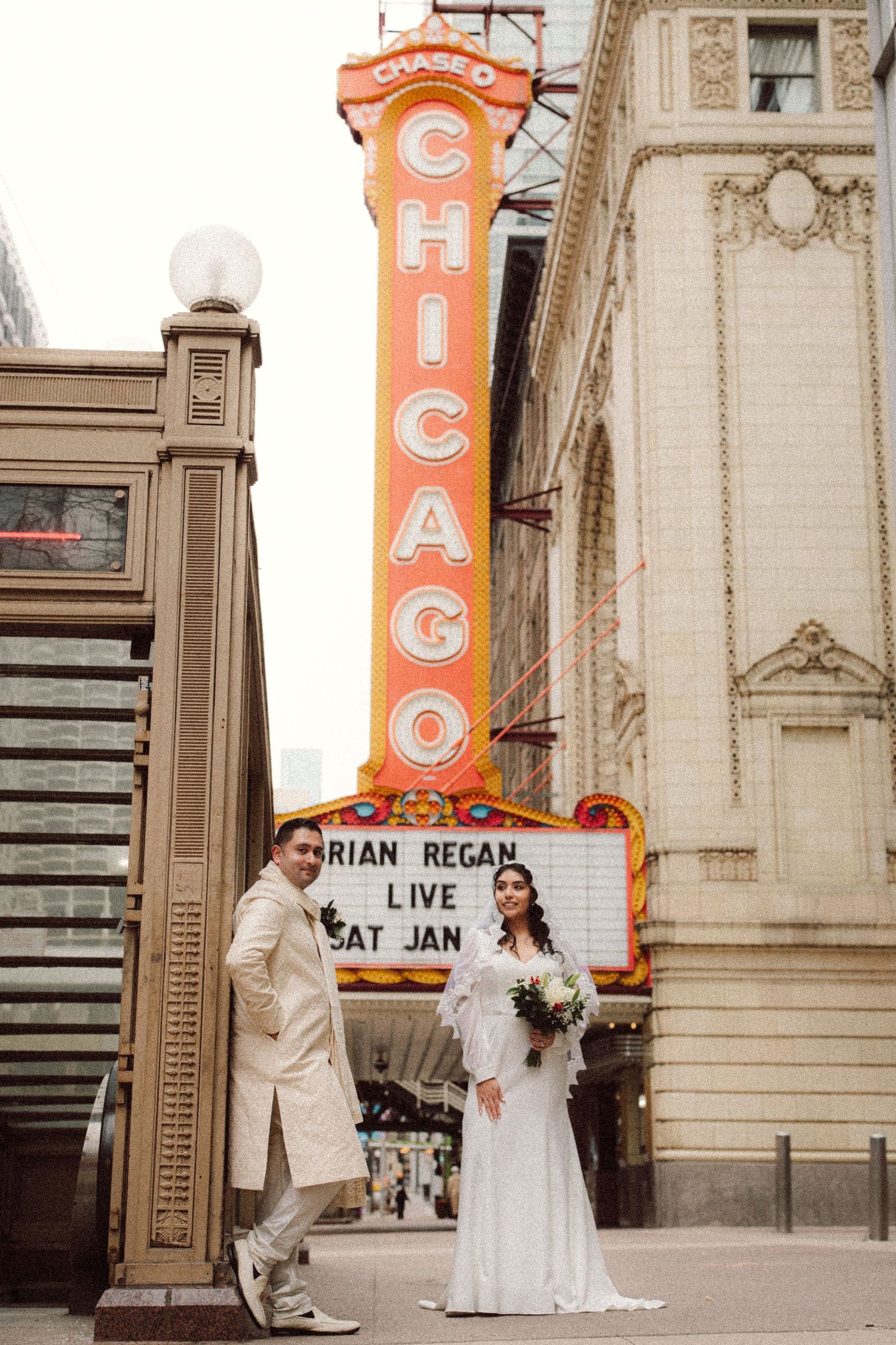 Wedding couple posing in front of the colorful Chicago Theatre marquee sign downtown.