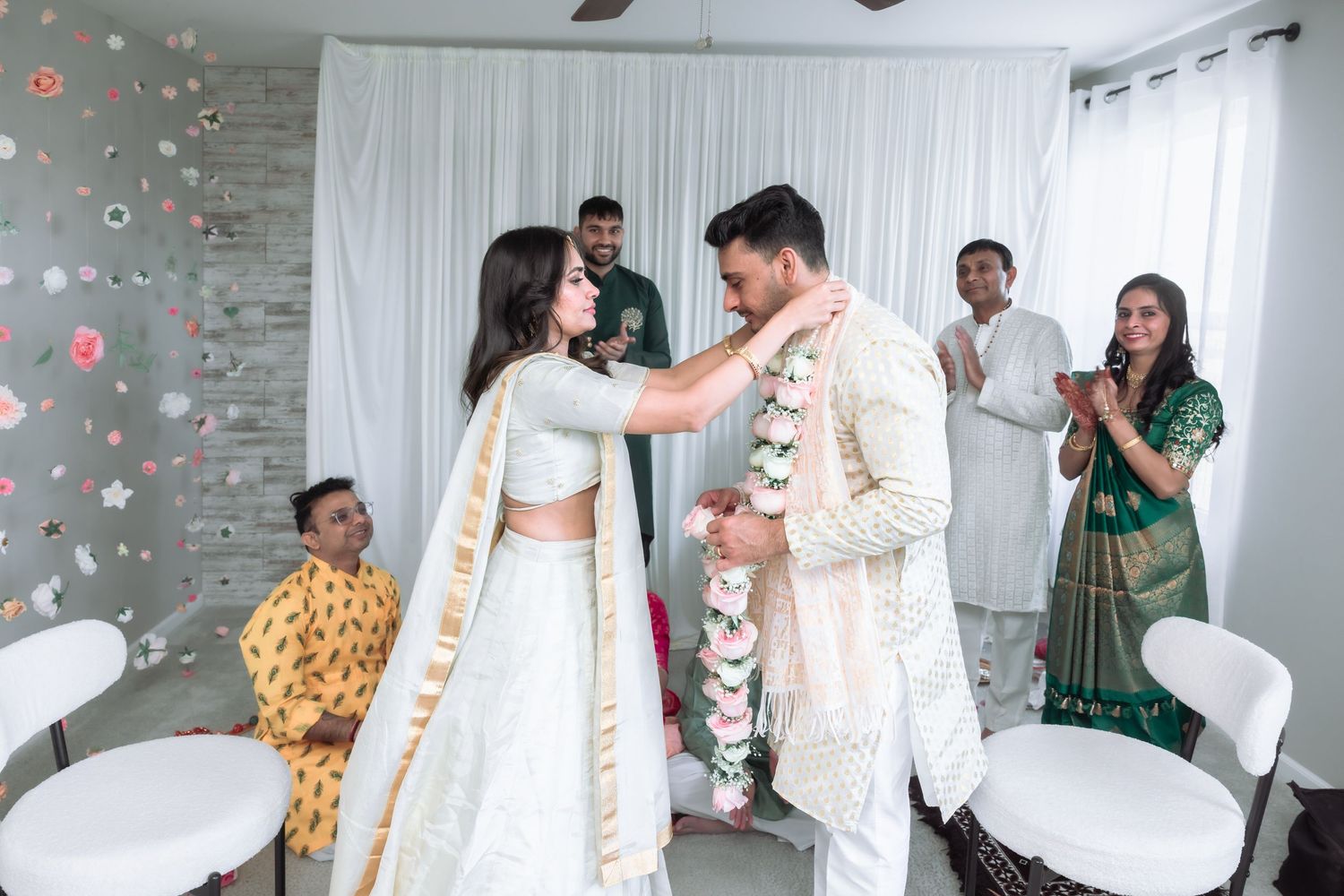 Groom places a floral garland on the bride during a joyful traditional Indian wedding ceremony.