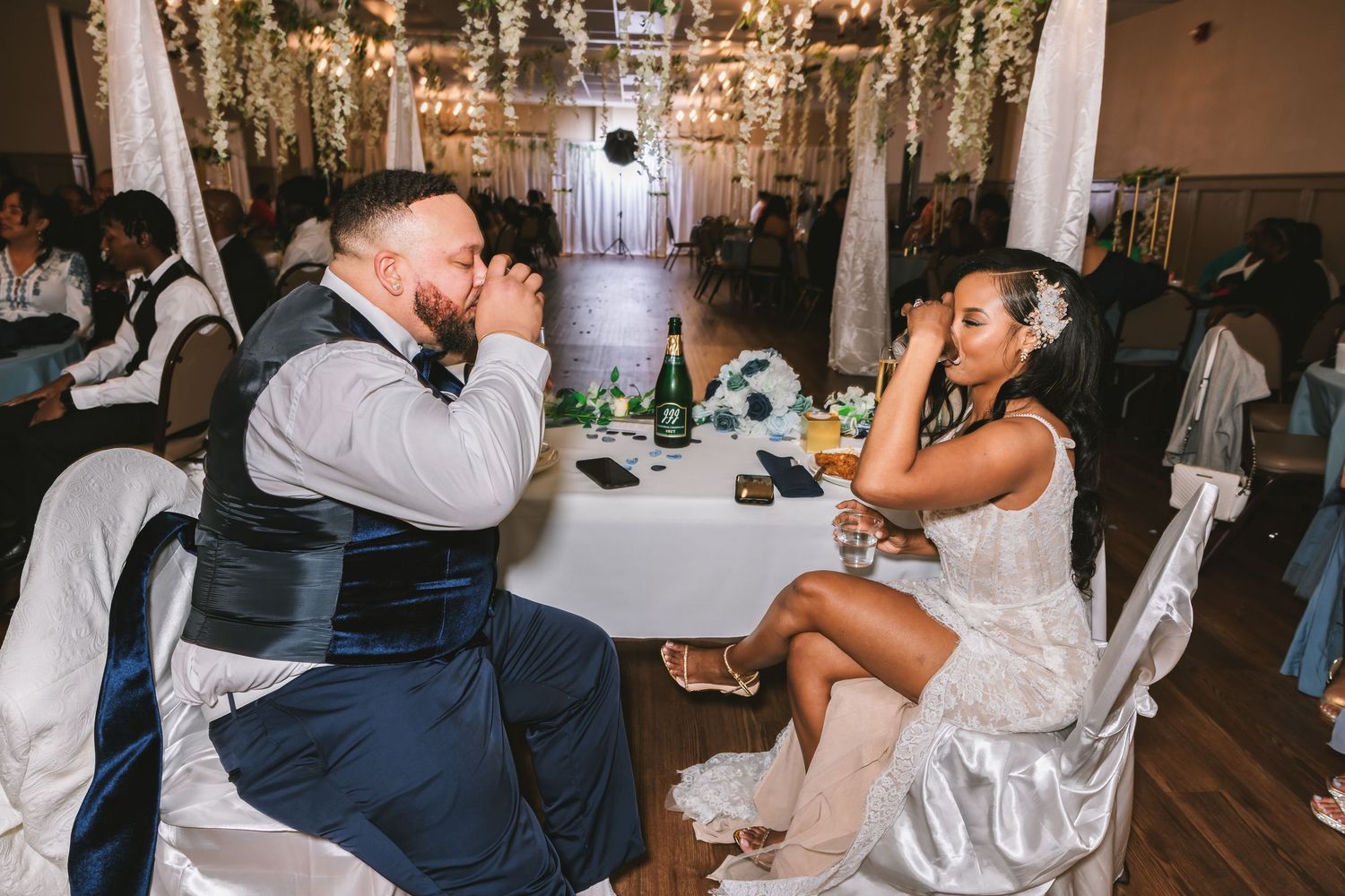 Bride and groom sharing a quiet moment at wedding reception table under warm string lights.