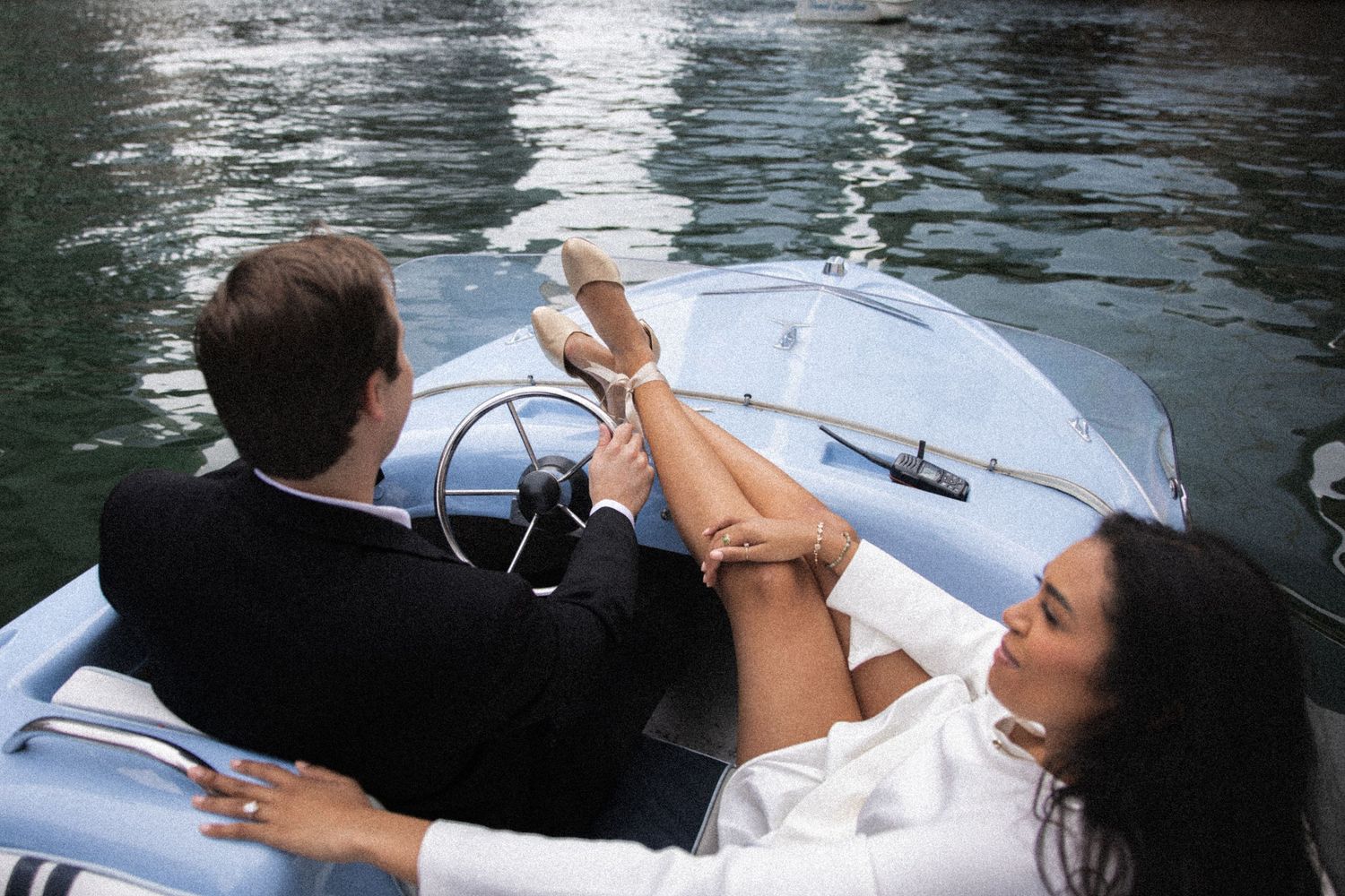 Aerial view of couple relaxing in a classic blue boat on the water, woman resting her legs up.
