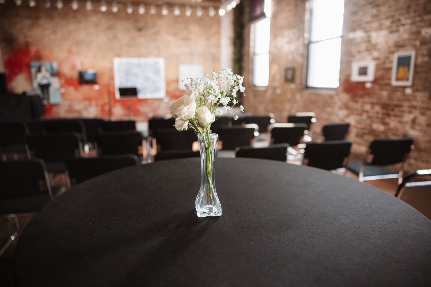 A single white flower in a glass vase centerpiece on a black tablecloth in an event venue.