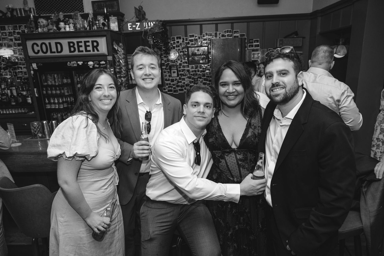Five friends pose together smiling at a bar in this fun black and white party photo.