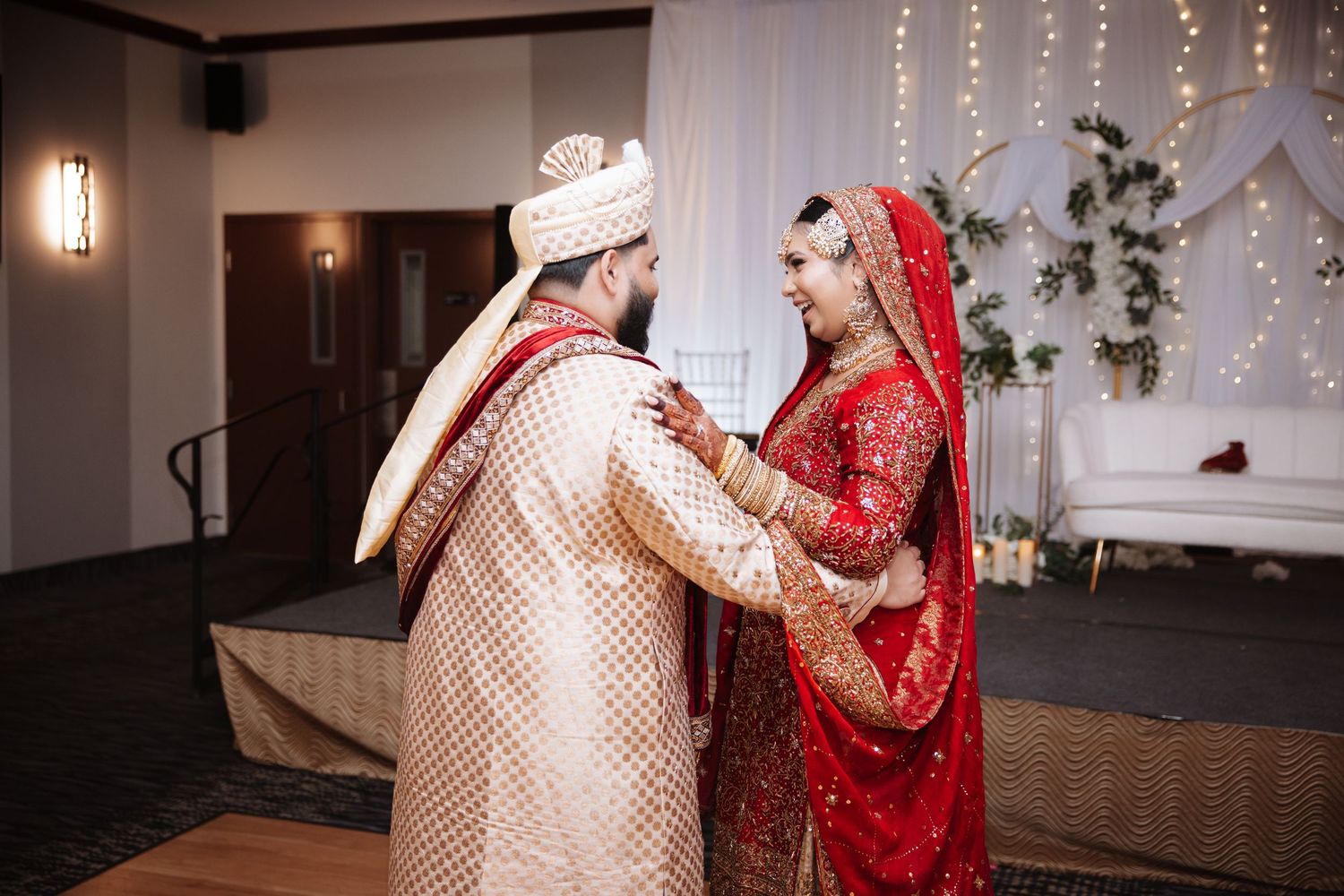 Indian couple in traditional bridal wear share a romantic first look during wedding ceremony.