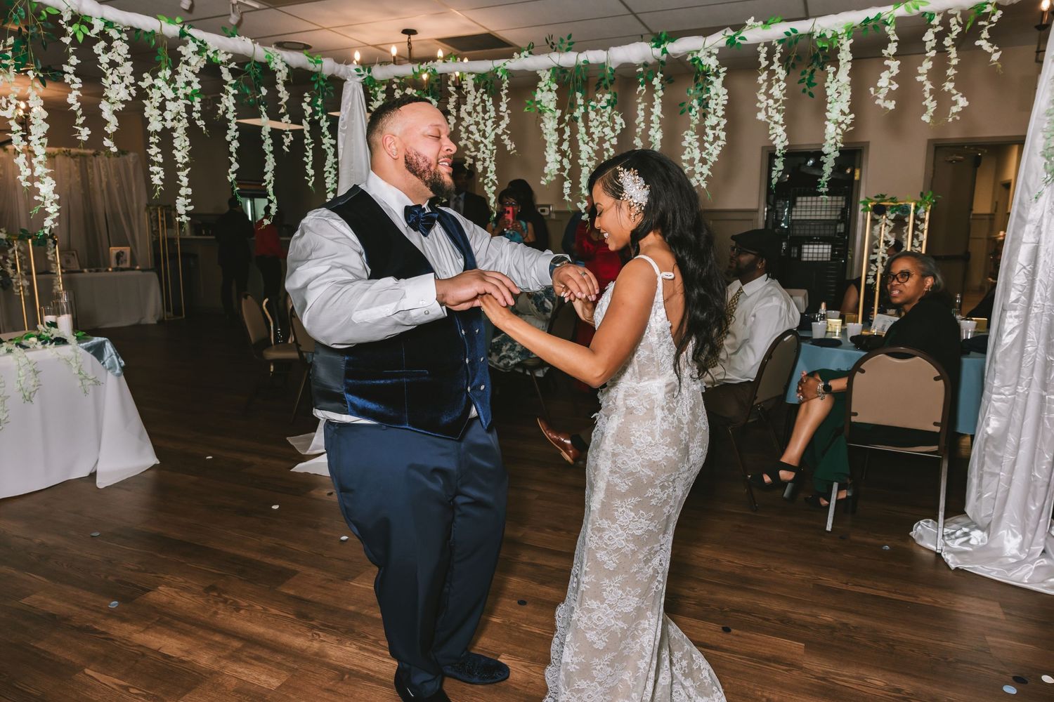Bride and groom sharing their first dance at wedding reception with hanging floral garlands.