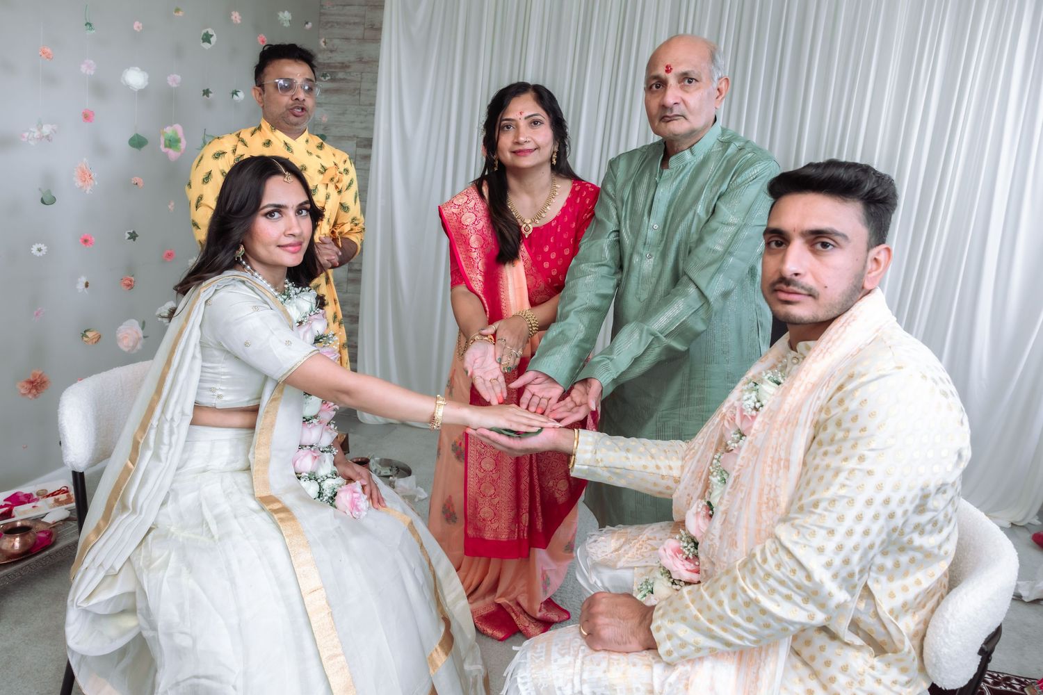 Bride and groom join hands during a traditional South Asian wedding ceremony with family members present.