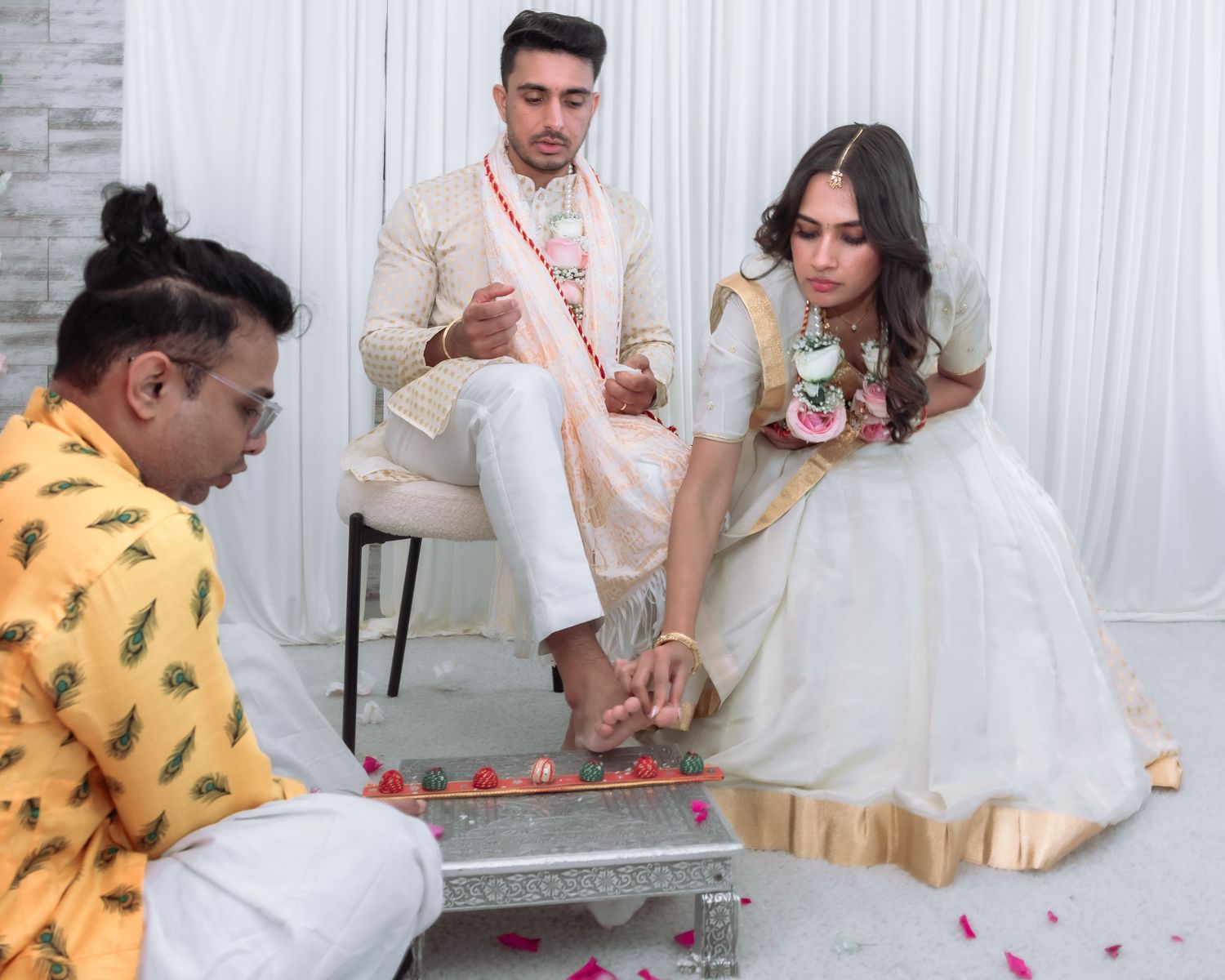 Hindu wedding ceremony with bride in white saree having feet washed in traditional ritual by priest.