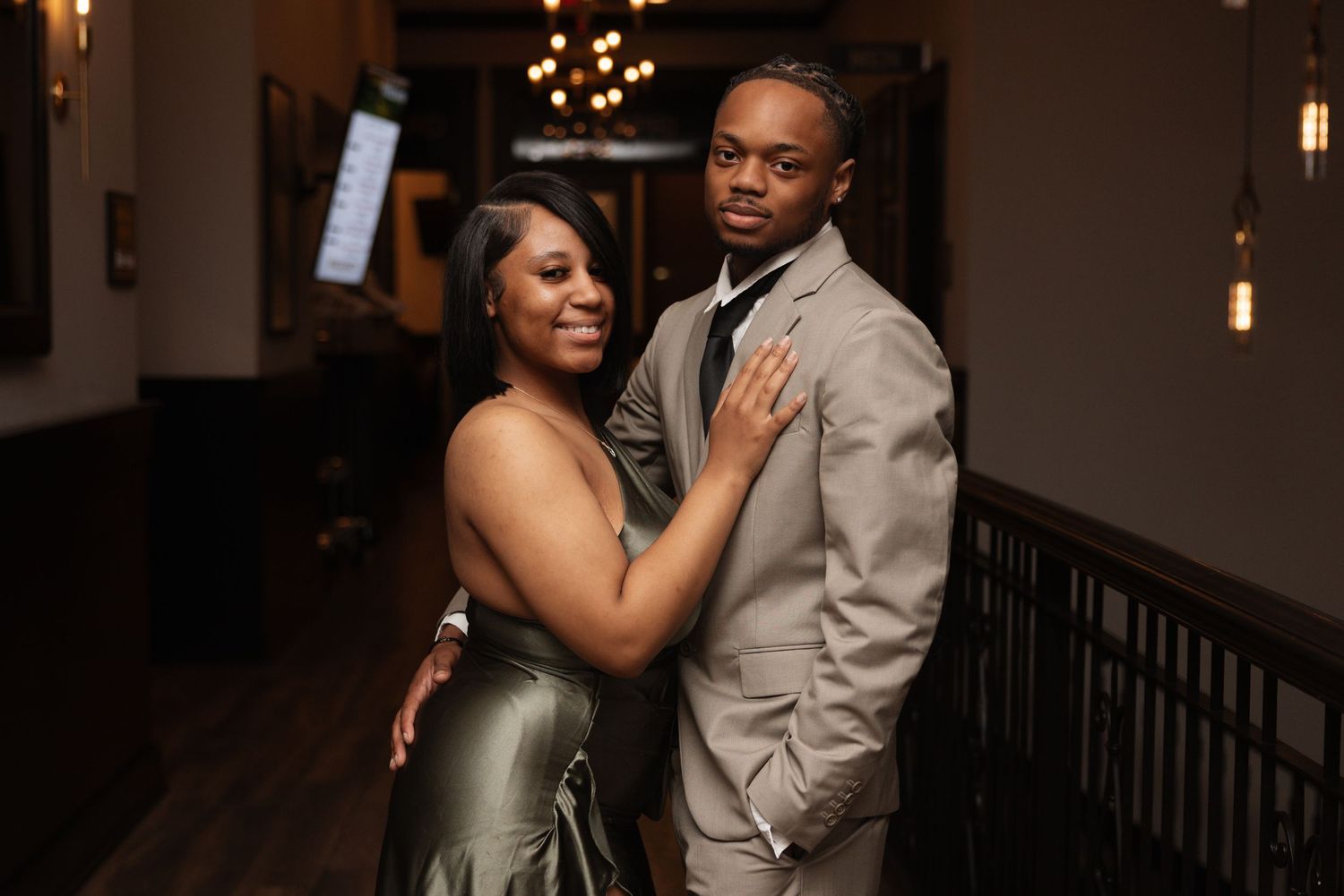 Couple embracing and smiling at wedding reception in dimly lit venue.