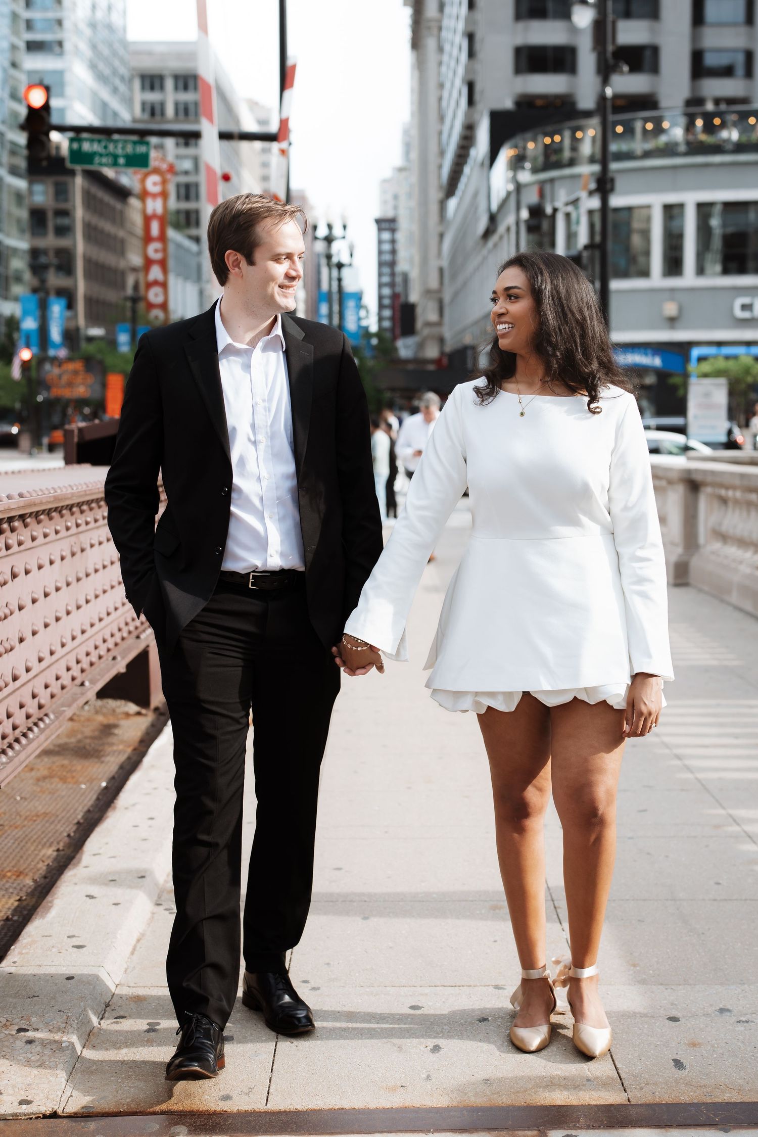 Happy interracial couple holding hands and walking along a Chicago city bridge sidewalk.