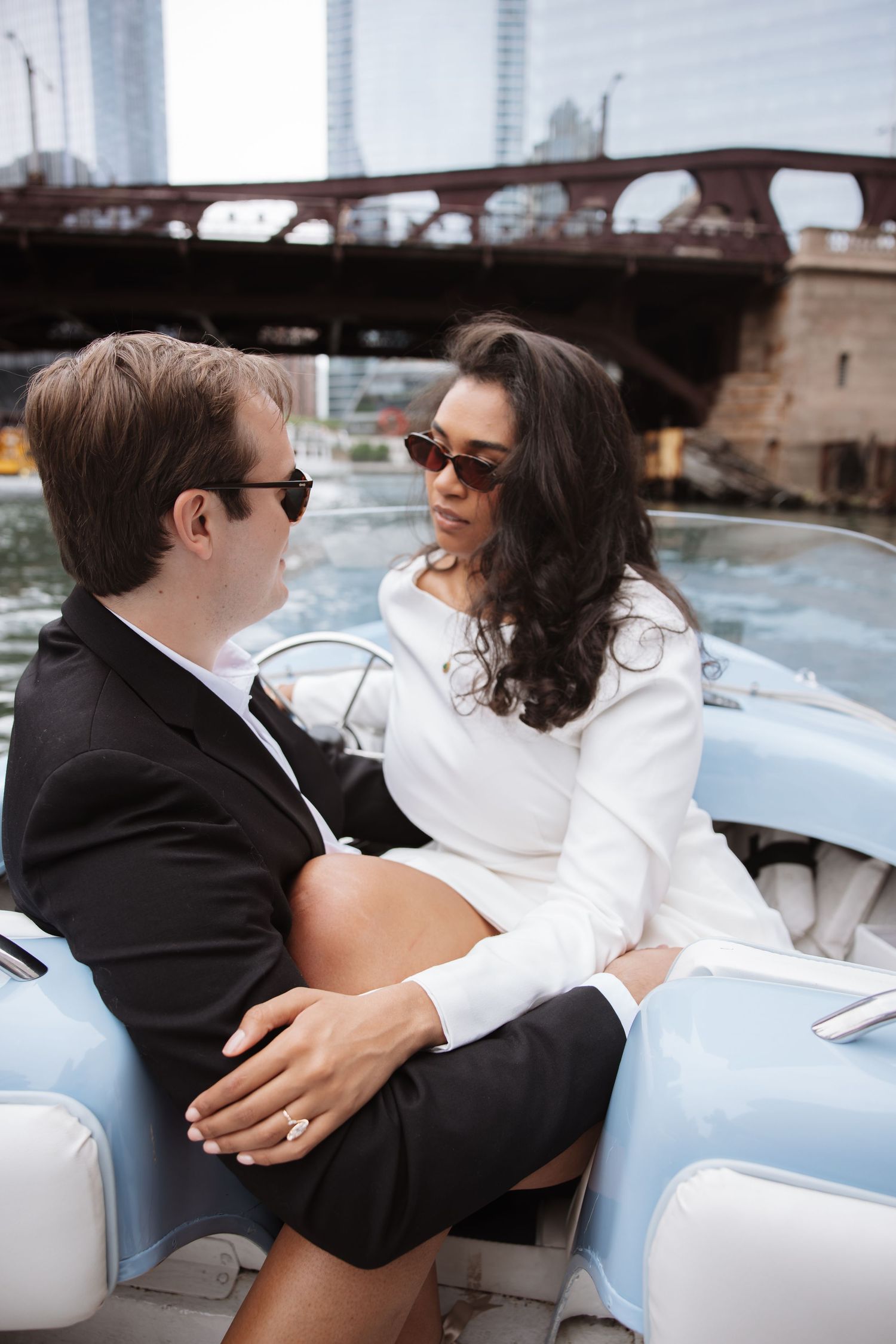 Couple in sunglasses sharing an intimate moment on a vintage blue boat along the Chicago River.