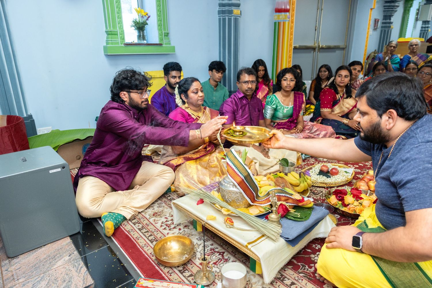 South Indian family performing traditional Hindu pooja ritual with offerings and sacred items.