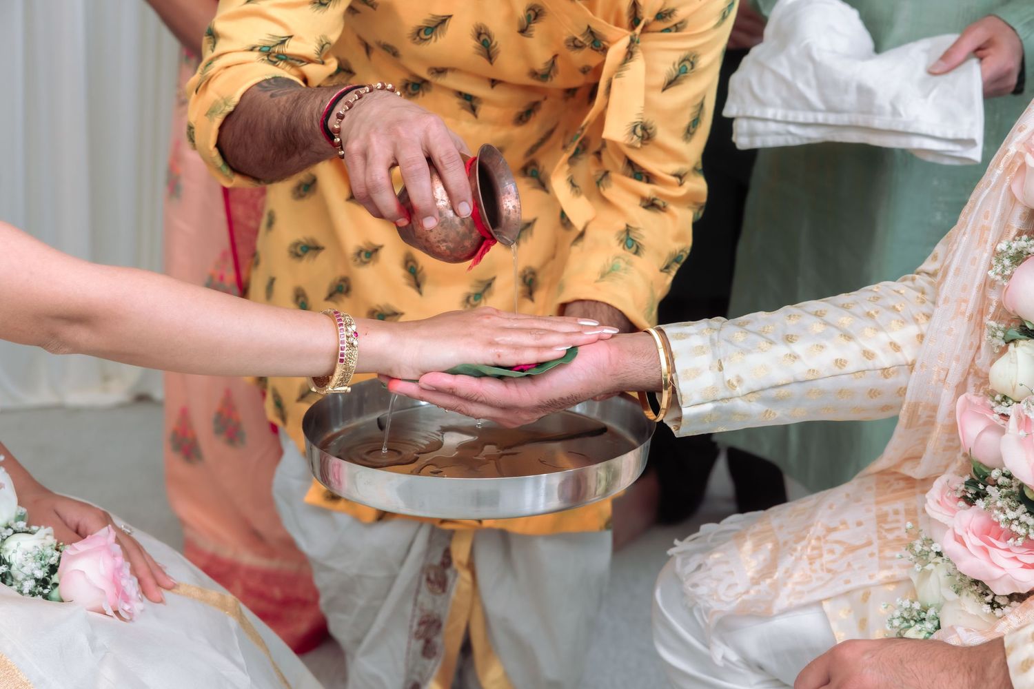 Hands performing Indian wedding ritual with water vessel during traditional Hindu marriage ceremony.
