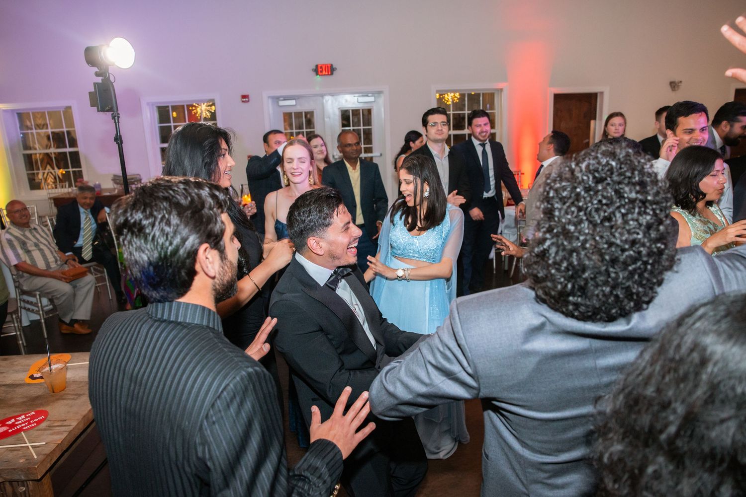 Guests dancing and socializing at a lively wedding reception with warm ambient lighting.