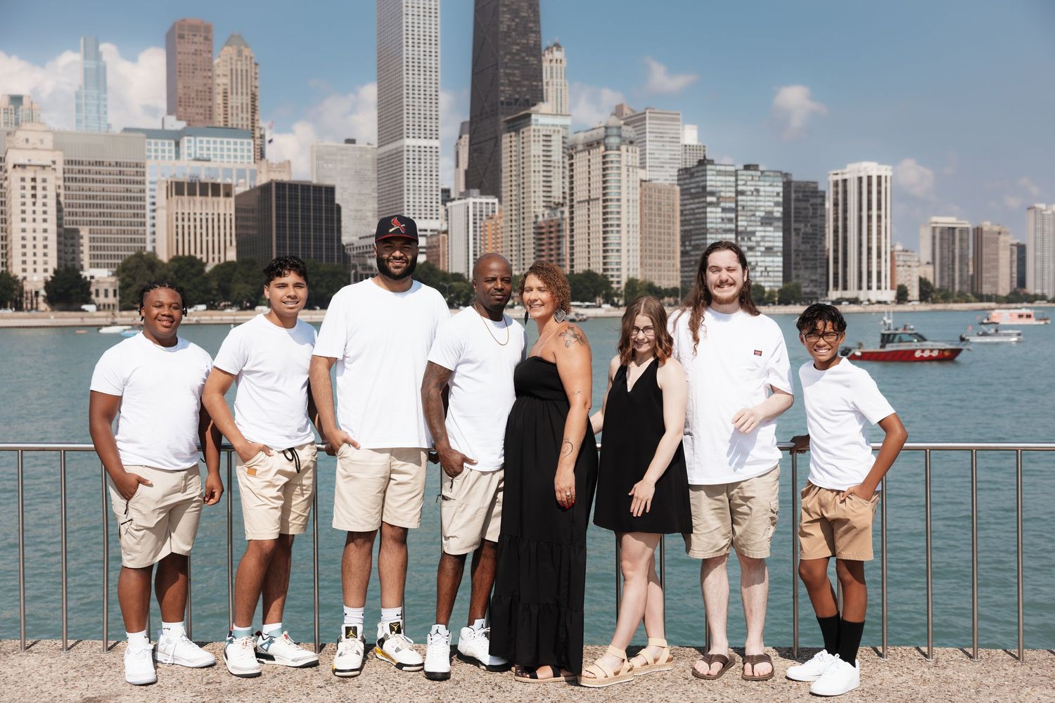 Group of seven people posing together with Chicago skyline and Lake Michigan in the background on a sunny day.