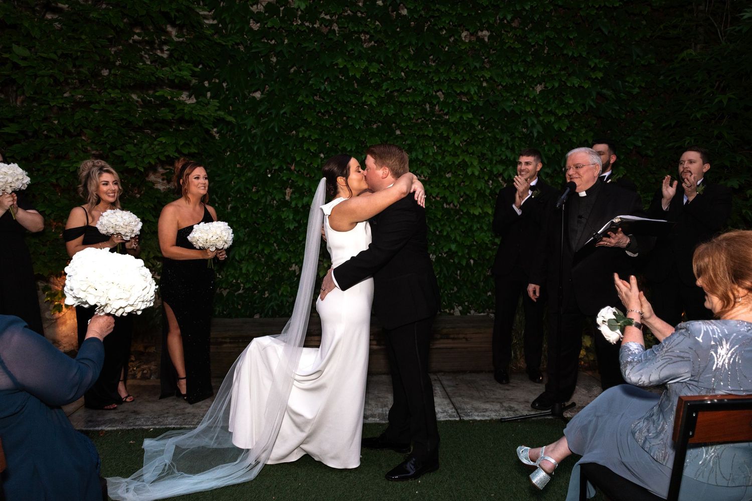 Newlyweds share first kiss as husband and wife at outdoor wedding ceremony.