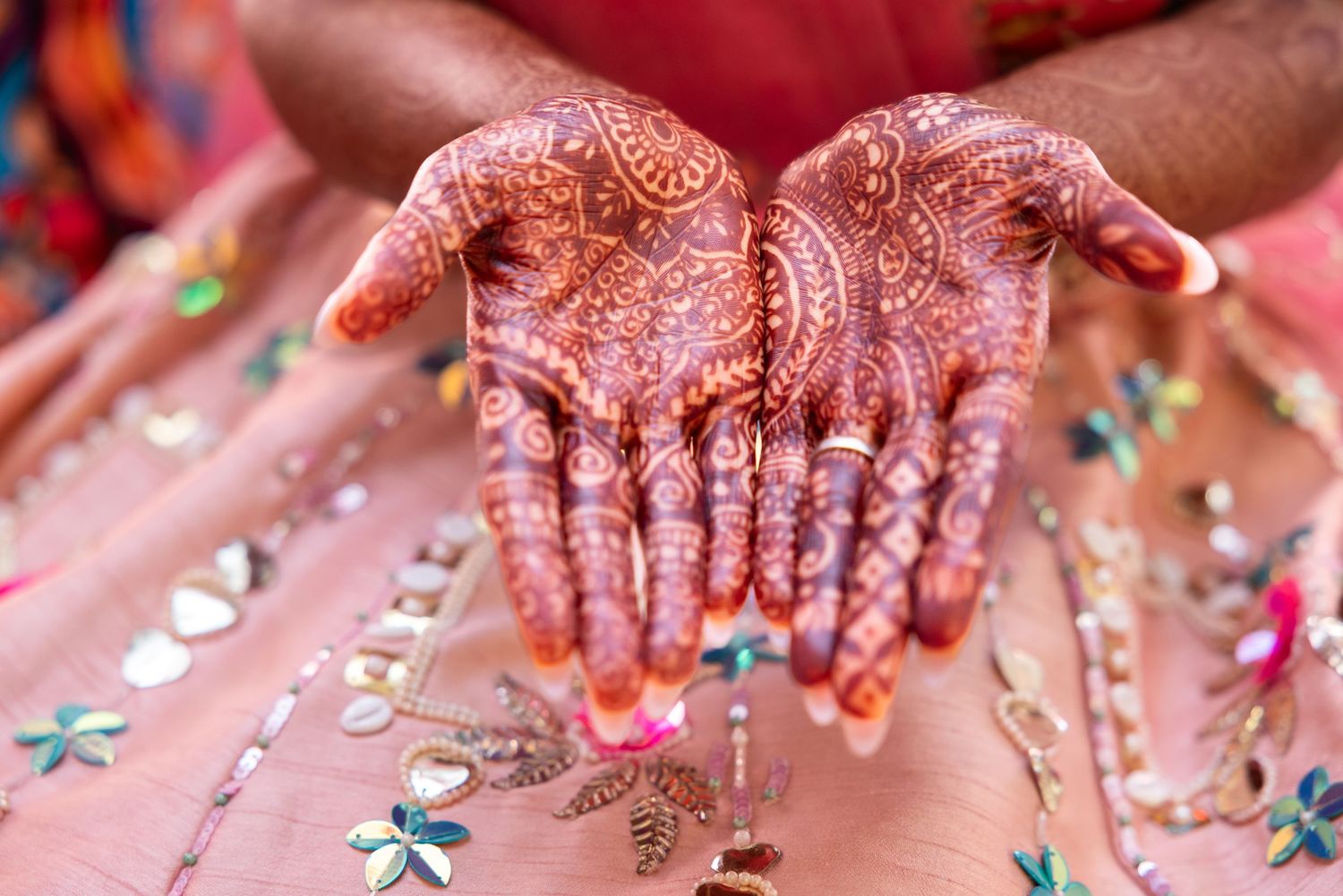 Close-up of Indian bride's hands adorned with detailed henna mehndi patterns.