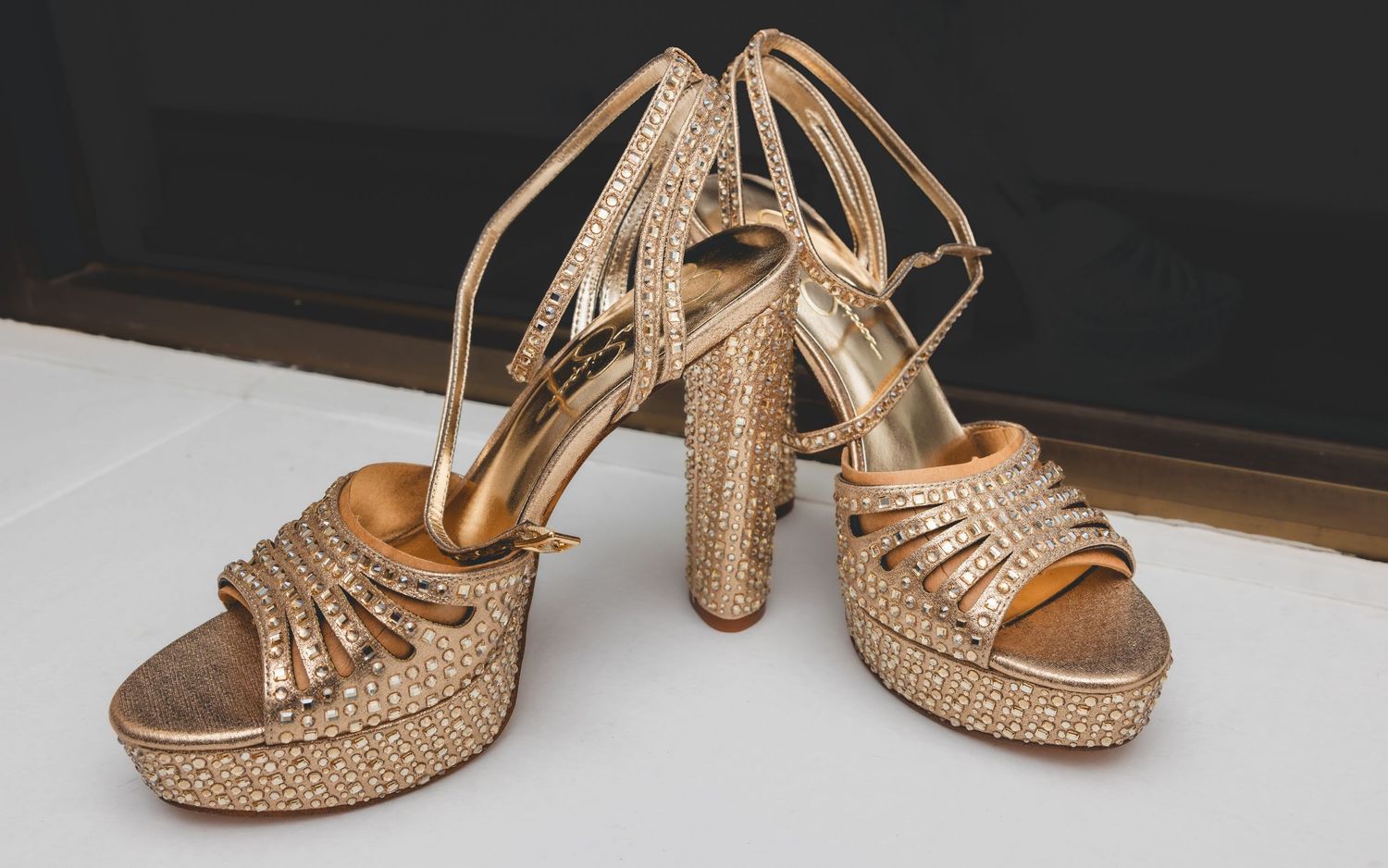 Gold rhinestone platform high heel wedding shoes displayed on a surface.