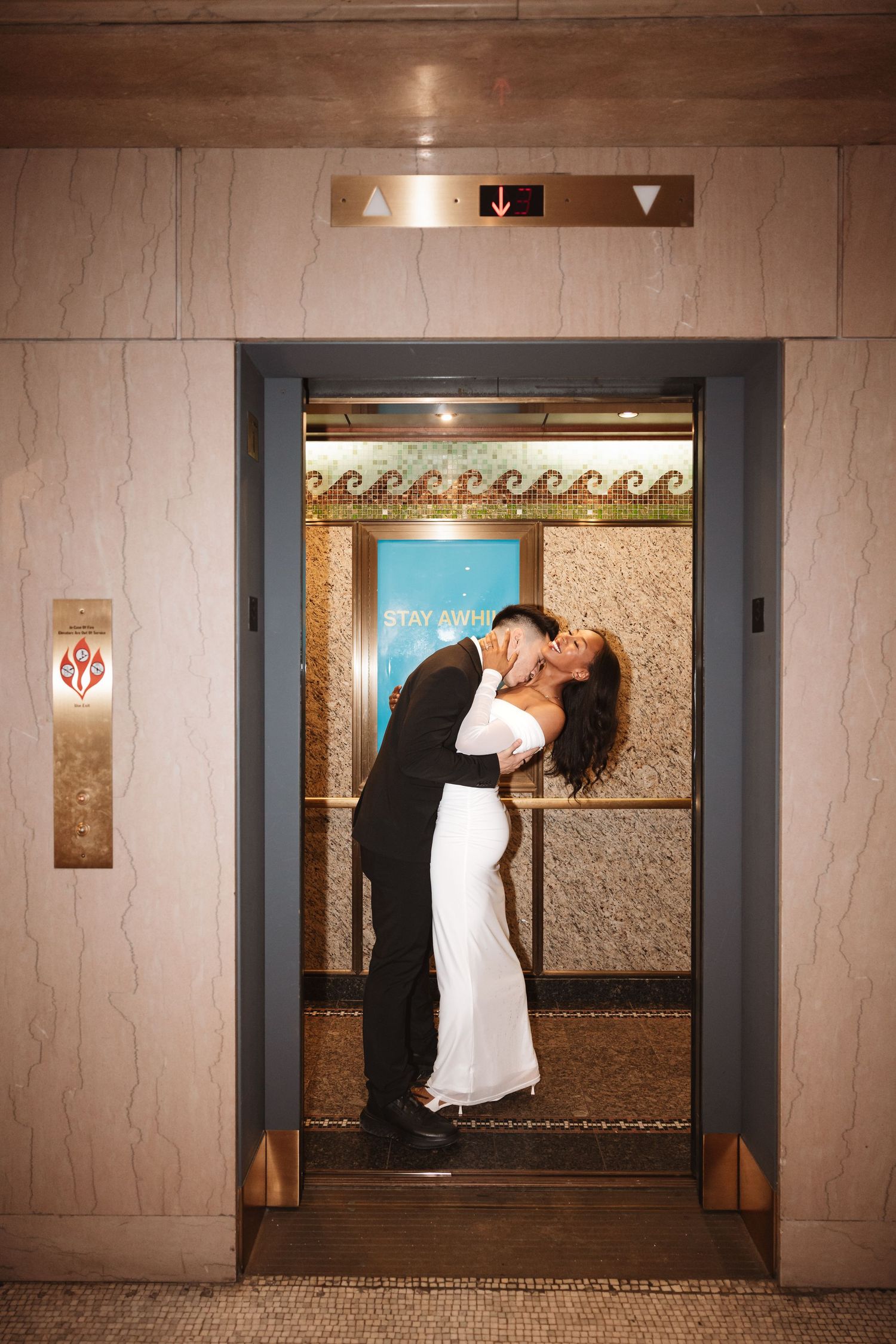 Bride and groom embracing in a kiss inside an elegant elevator with gold accents.Chicago Wedding Photographer